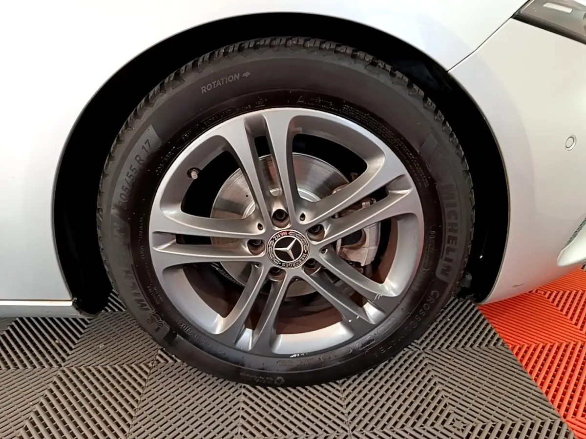 Gros plan sur la roue avant gauche gris clair d'une Mercedes Classe A 180 d Business Line 2020 avec jante alliage et logo Mercedes.