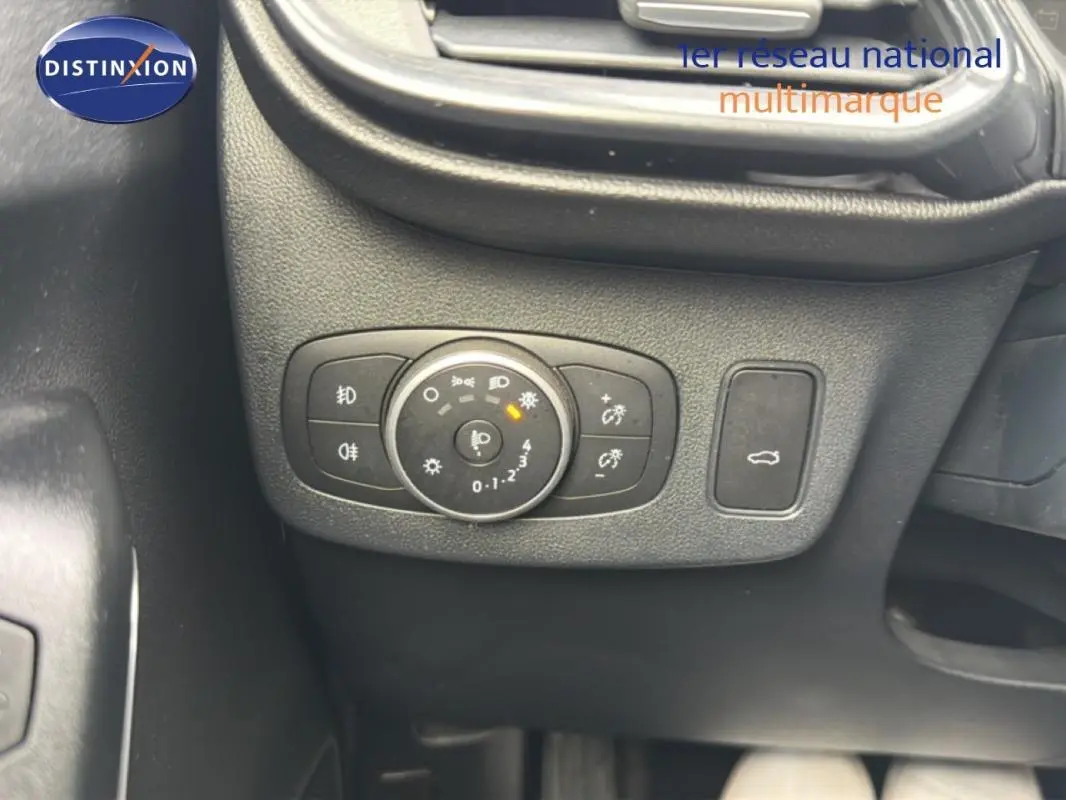 Gros plan sur le bouton de commande des feux et ouverture du coffre dans l’habitacle noir du Ford Puma blanc 2020.