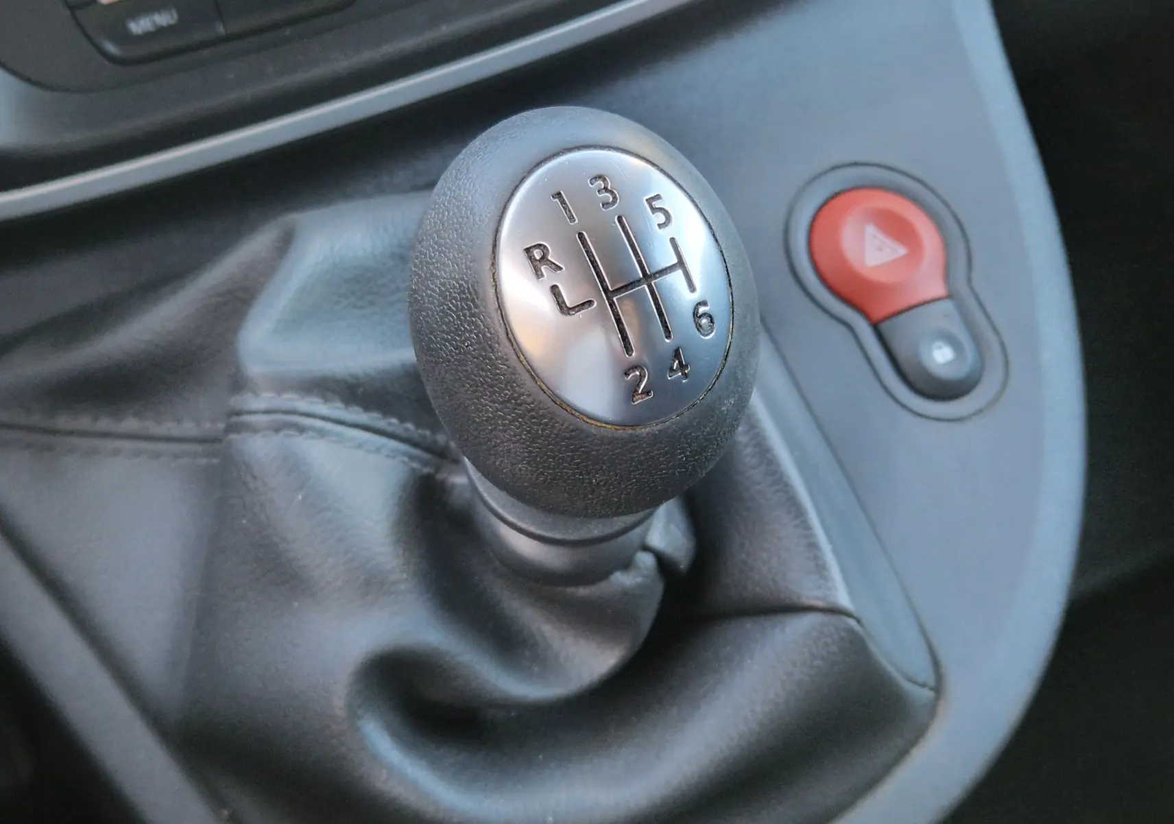 Gros plan sur le levier de vitesses manuel du Renault Kangoo blanc, avec bouton de warning rouge visible à droite.