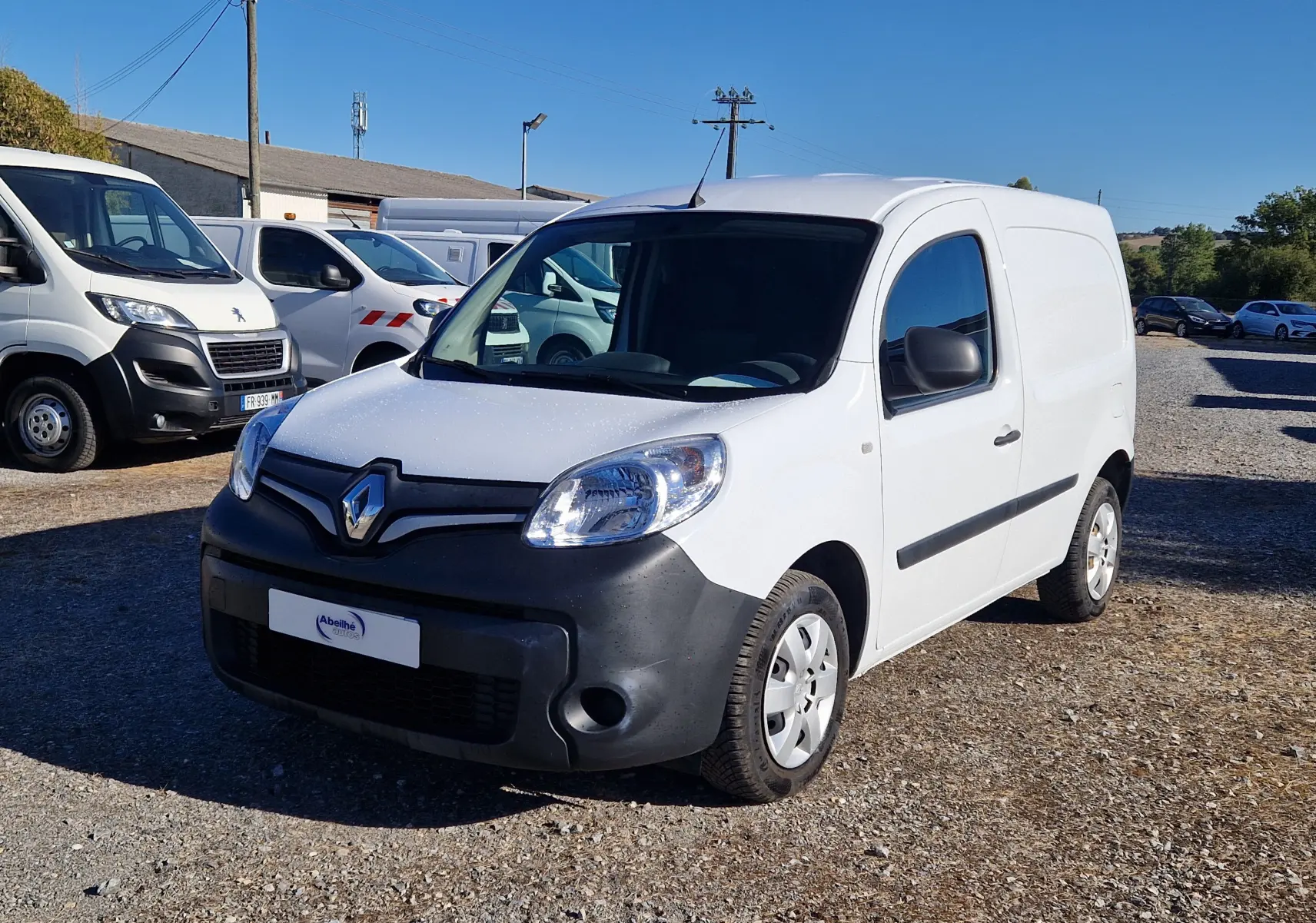 Renault Kangoo blanc vue 3/4 avant droit, fourgonnette utilitaire avec pare-chocs noir mat et jantes acier.