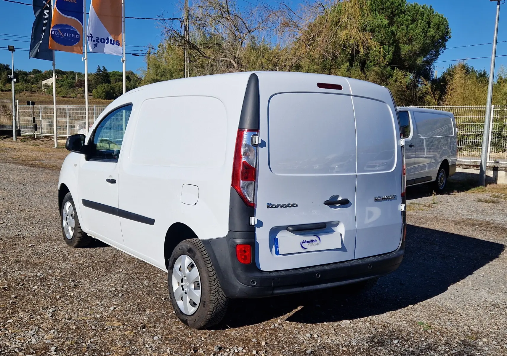 Renault Kangoo blanc vue 3/4 arrière droit, fourgonnette utilitaire avec portes arrière battantes et pare-chocs noirs.