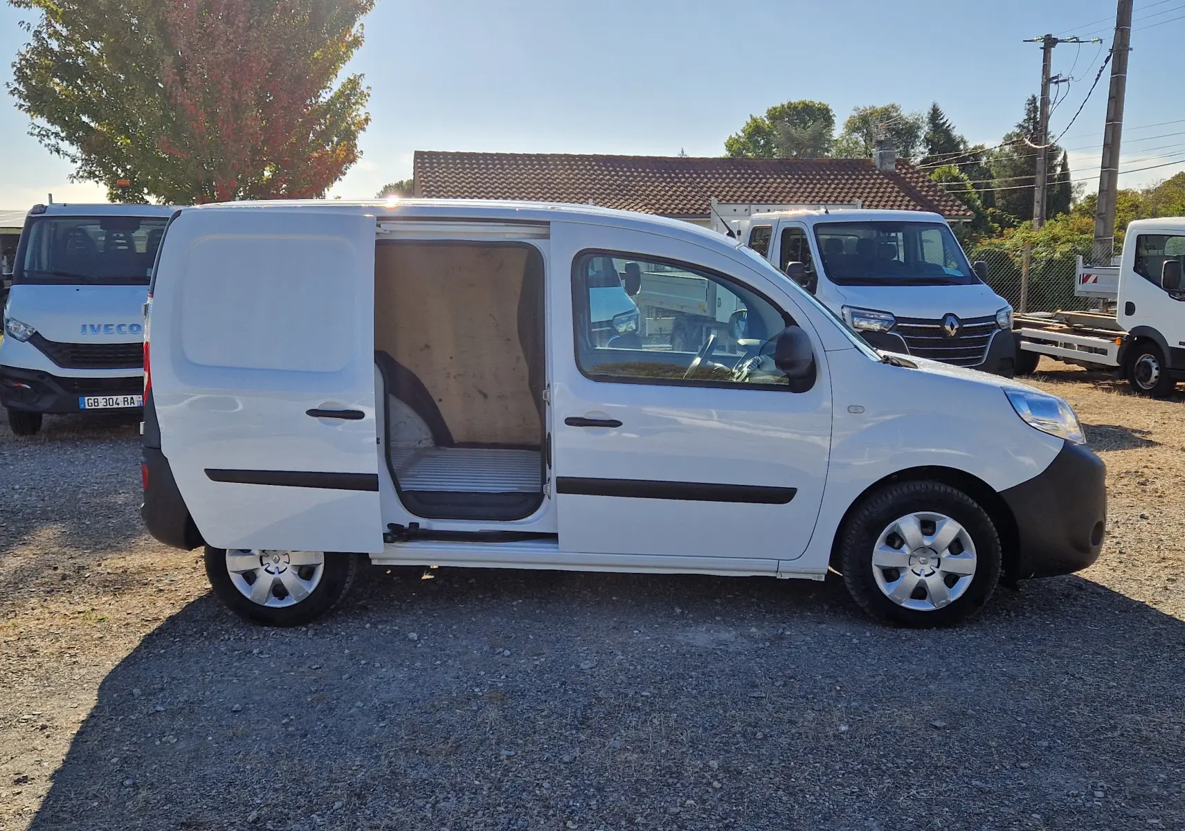 Vue de profil côté droit d'un Renault Kangoo blanc 2021 avec porte latérale coulissante ouverte montrant l'espace de chargement.