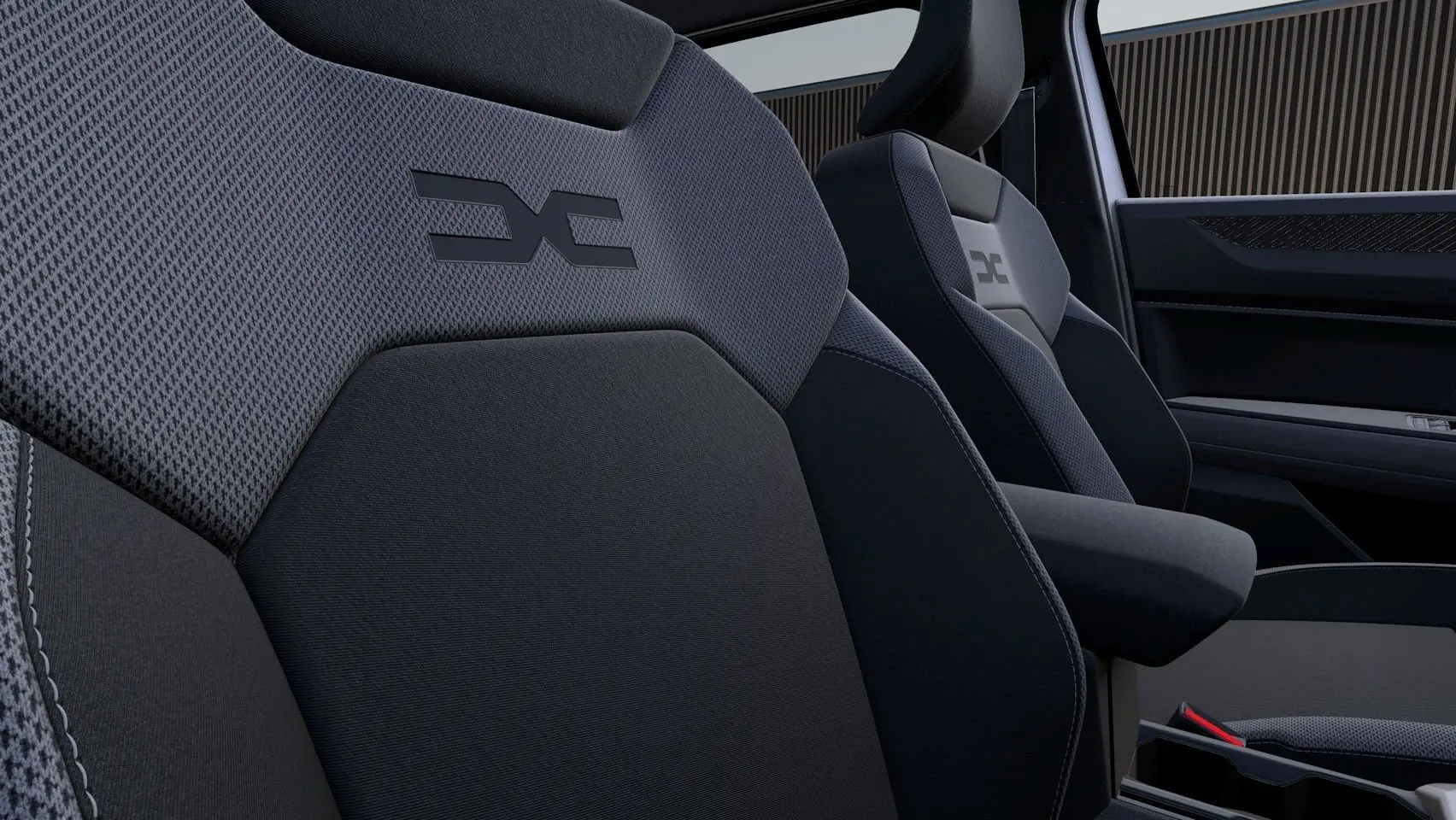 Gros plan sur les sièges avant gris foncé du Dacia Duster 2026 avec logo distinctif brodé sur les appuie-têtes.