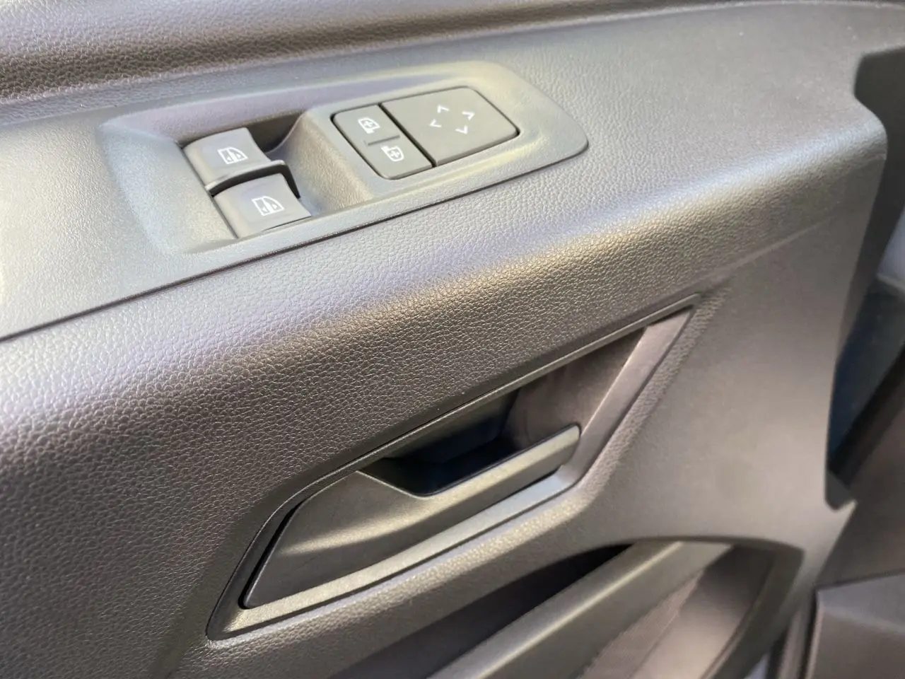 Gros plan sur la poignée intérieure et les commandes de lève-vitres côté conducteur du Renault Master gris urbain.
