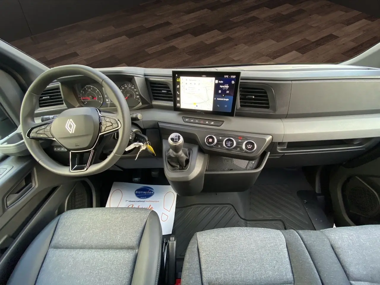 Vue intérieure frontale du tableau de bord du Renault Master 2025 avec volant, écran tactile et banquette passager grise.