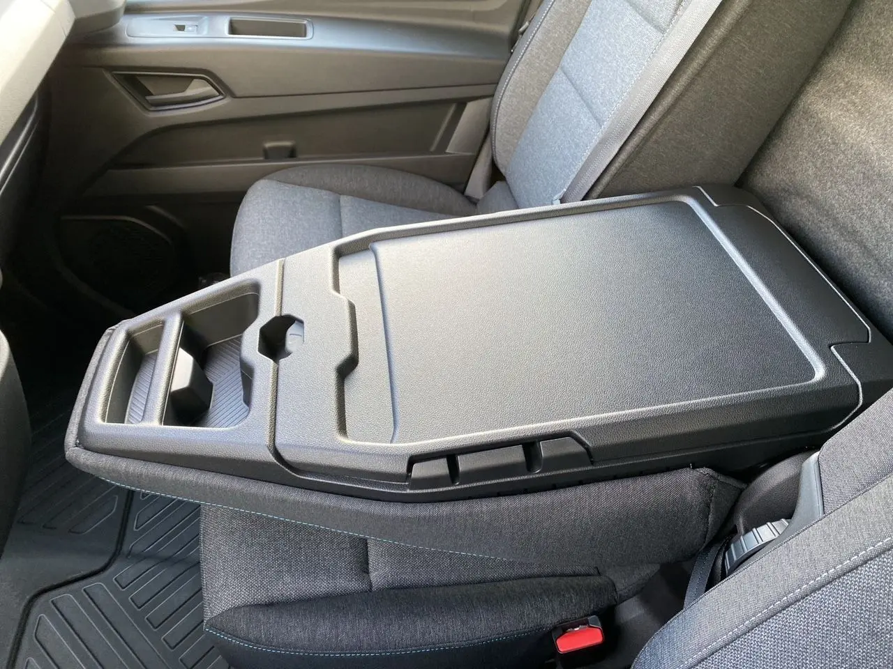 Détail intérieur montrant la banquette passager grise avec bureau mobile et rangements dans un Renault Master 2025.