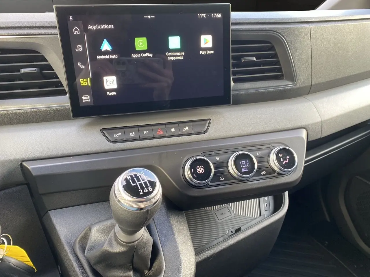 Vue rapprochée du tableau de bord du Renault Master 2025 avec écran tactile, climatisation et levier de vitesse manuel.