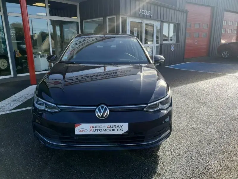 Volkswagen Golf 1.5 eTSI Style noir nacré vue de face devant un garage avec enseigne Accueil.