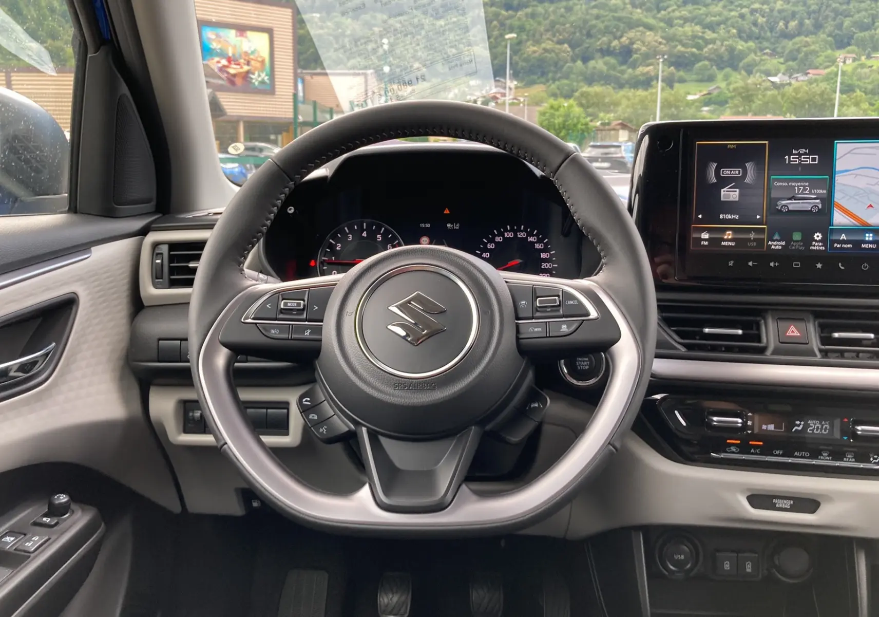 Vue intérieure centrée sur le volant cuir multifonctions d'une Suzuki Swift 2025 avec tableau de bord numérique et écran tactile.