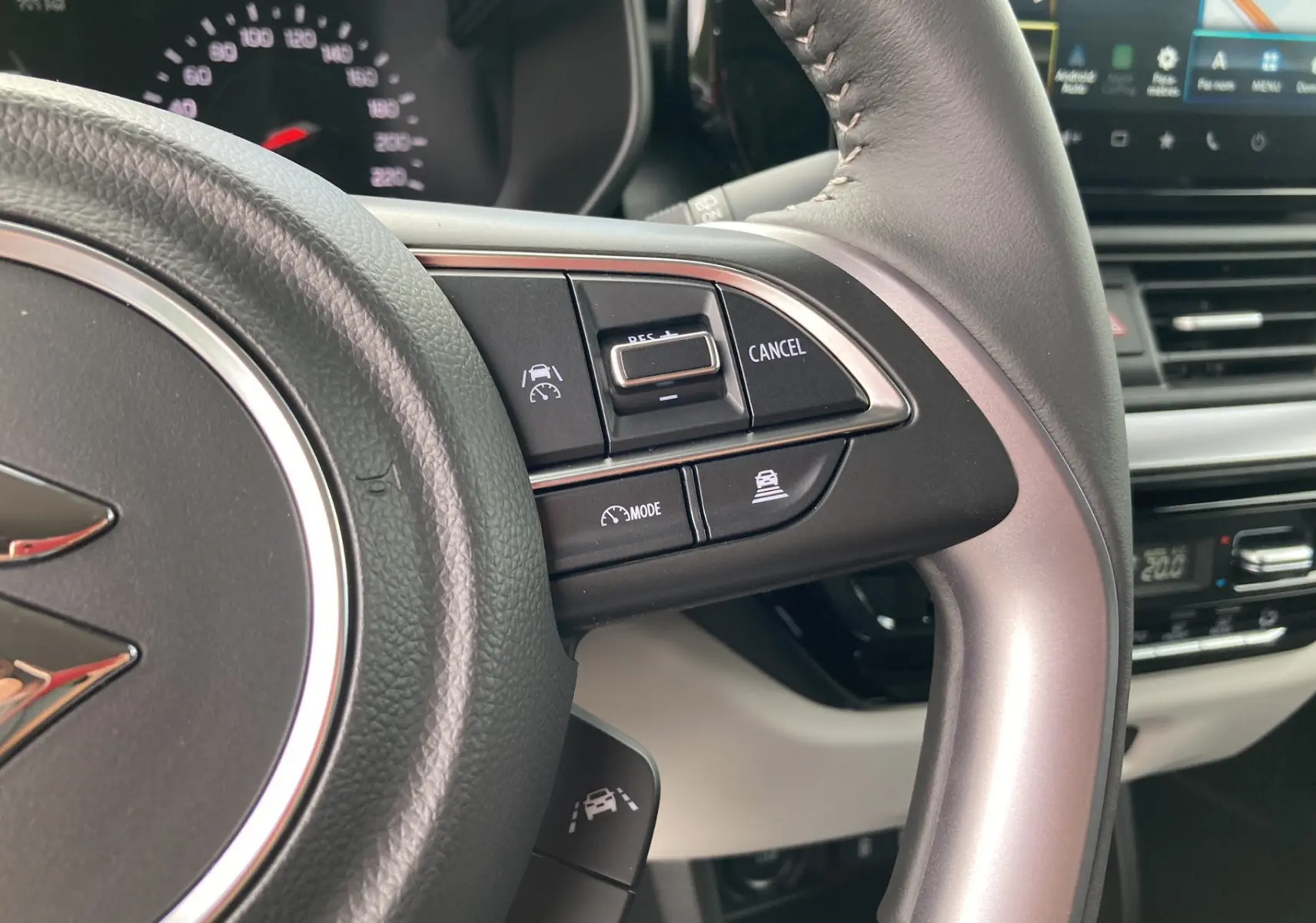 Gros plan sur le volant cuir multifonctions côté droit de la Suzuki Swift 2025, avec commandes de régulateur et aides à la conduite visibles.