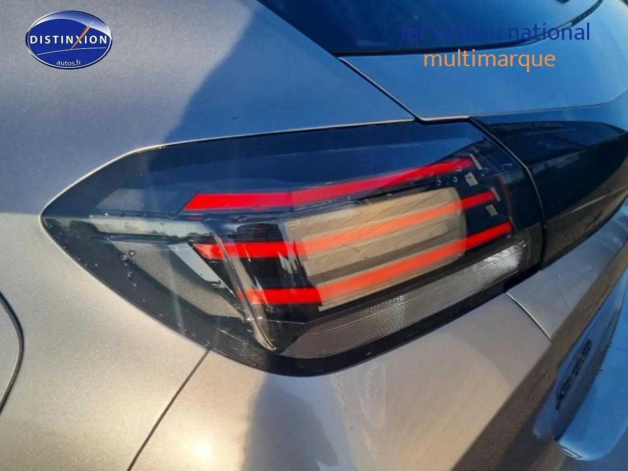 Gros plan sur le feu arrière droit rouge et noir d'une Peugeot 208 1.2 100 Allure gris Artense, vue arrière partielle.