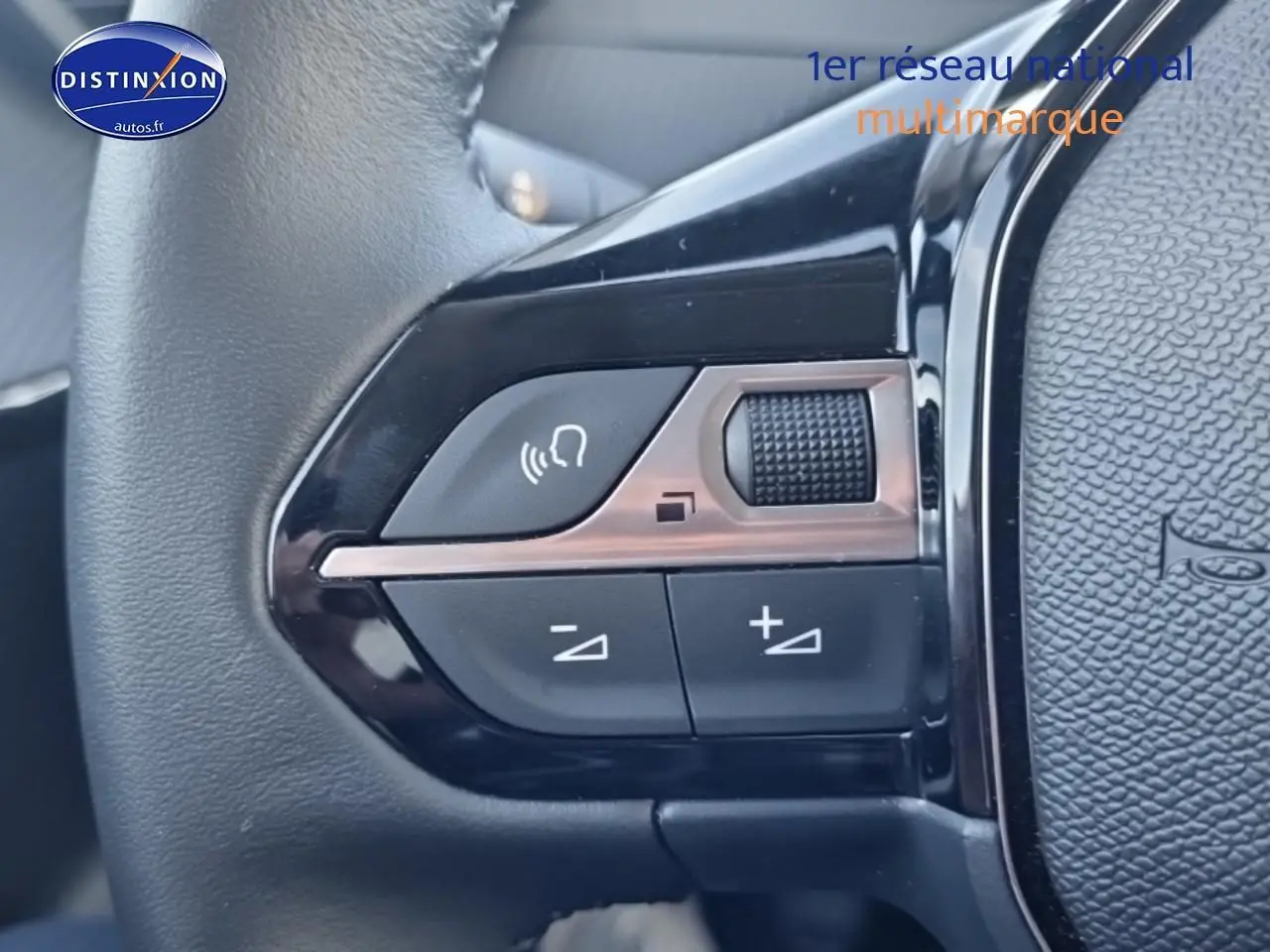 Gros plan sur les commandes audio au volant noir de la Peugeot 208 1.2 100 Allure gris Artense, côté gauche.