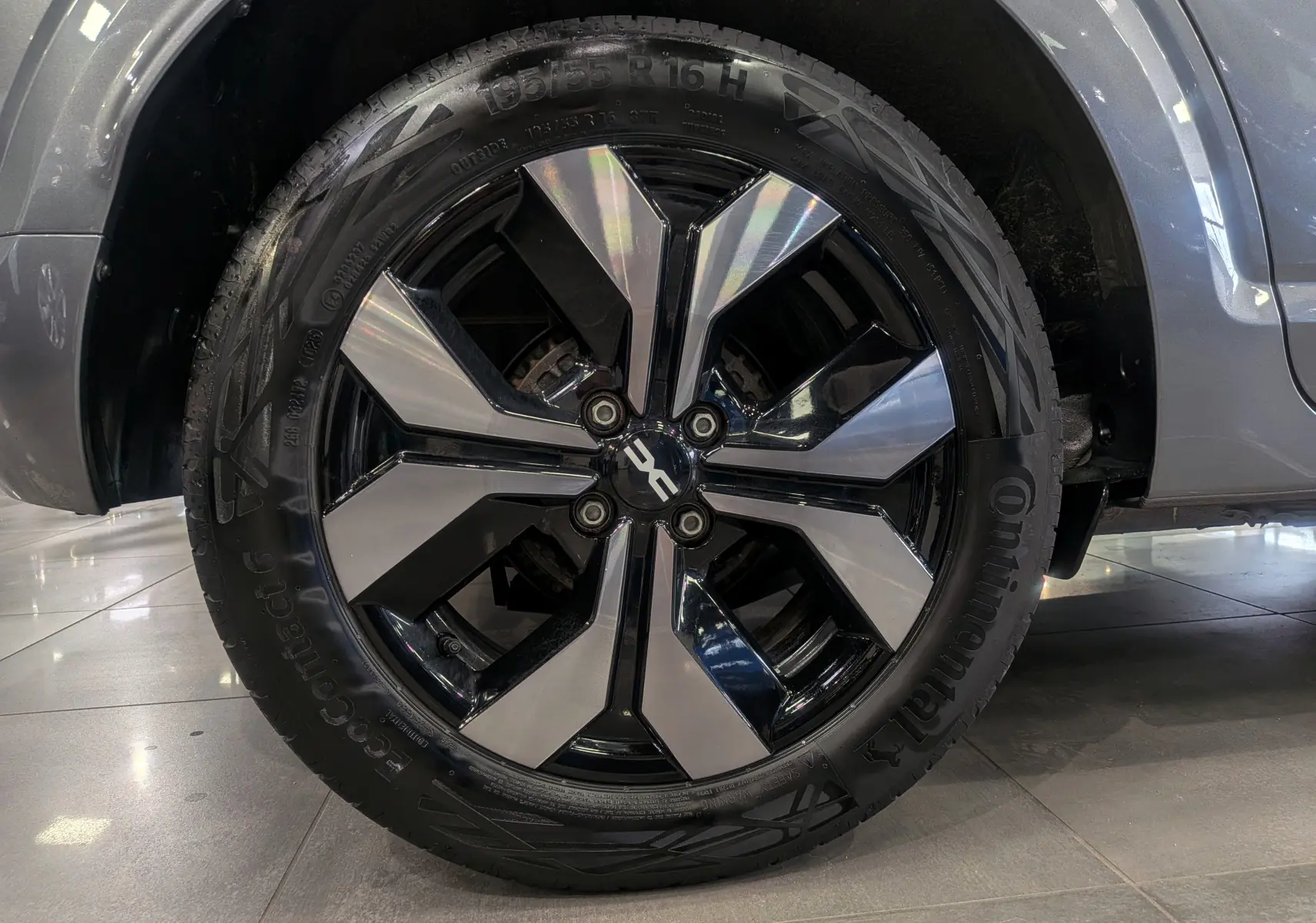 Gros plan sur la roue avant droite d'une Dacia Sandero TCe 90 CH Journey gris schiste avec jante alliage bicolore.