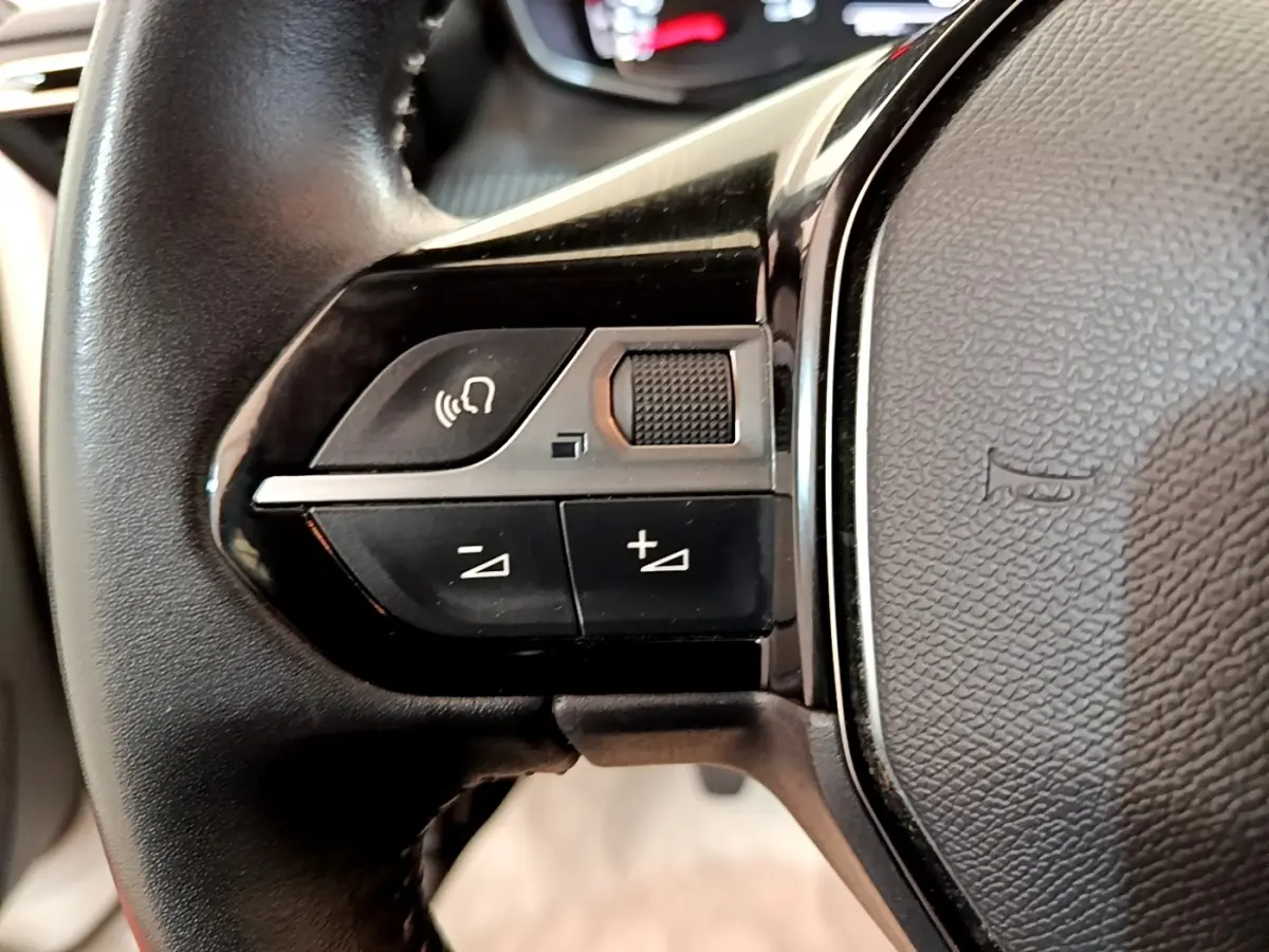 Gros plan sur les commandes gauche du volant cuir multifonctions du Peugeot 2008 blanc, version BlueHDi 110 S&S Active Business.