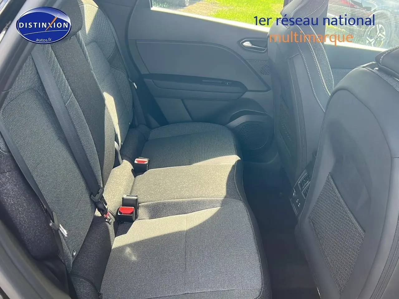 Vue intérieure montrant la banquette arrière grise du Renault Captur 2025 avec ceintures et filets de rangement sur les sièges avant.