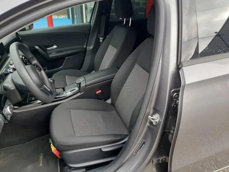 Vue intérieure côté conducteur de la Mercedes Classe A 160 Style Line 2018 en gris montagne métallisé avec sièges tissu noir et console centrale.