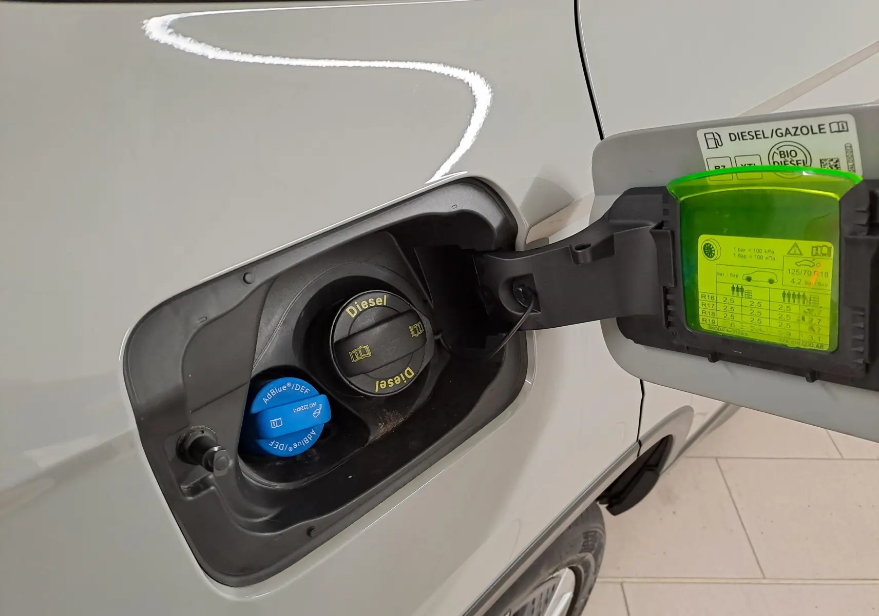 Bouchon de réservoir diesel ouvert sur le côté gauche d’un Skoda Karoq gris perle, avec étiquette pression pneus visible.