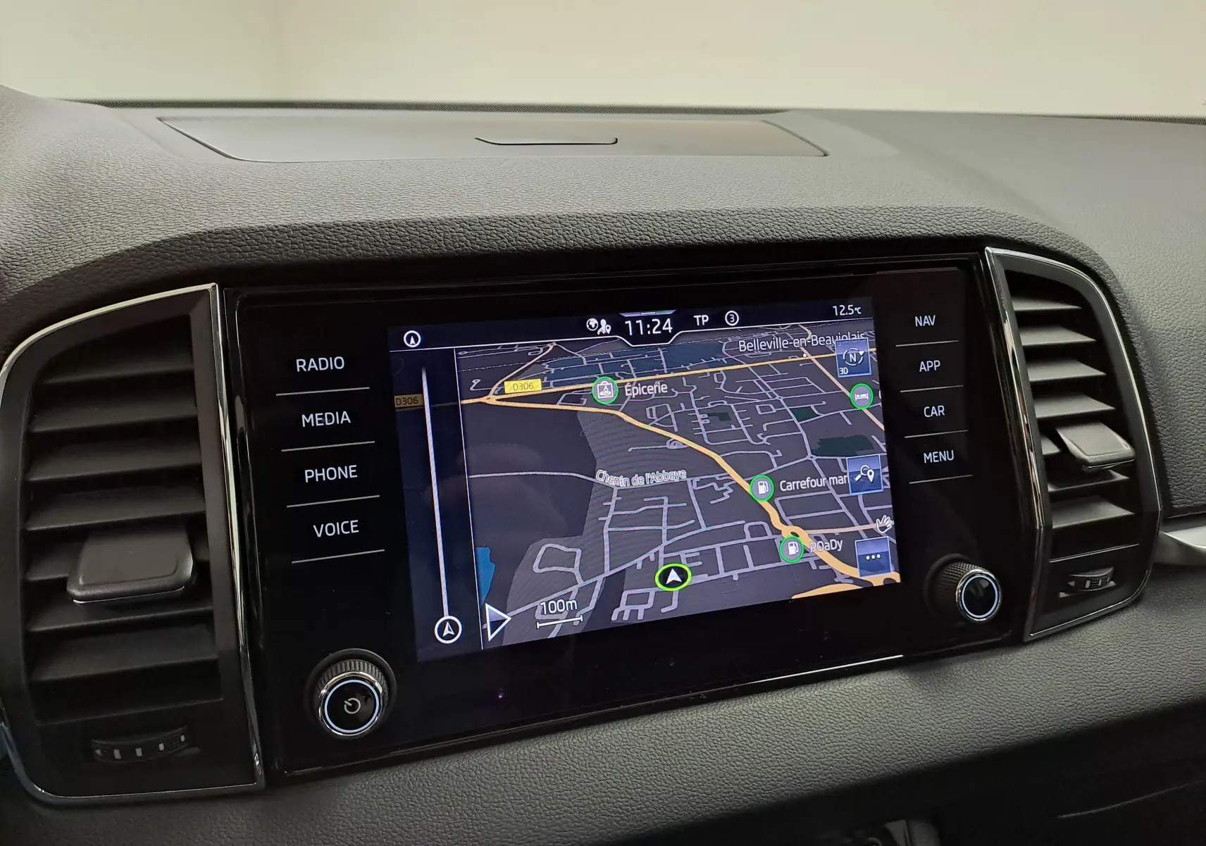 Écran tactile central du Skoda Karoq 2023 affichant la navigation, entouré de commandes multimédia et aérateurs noirs.