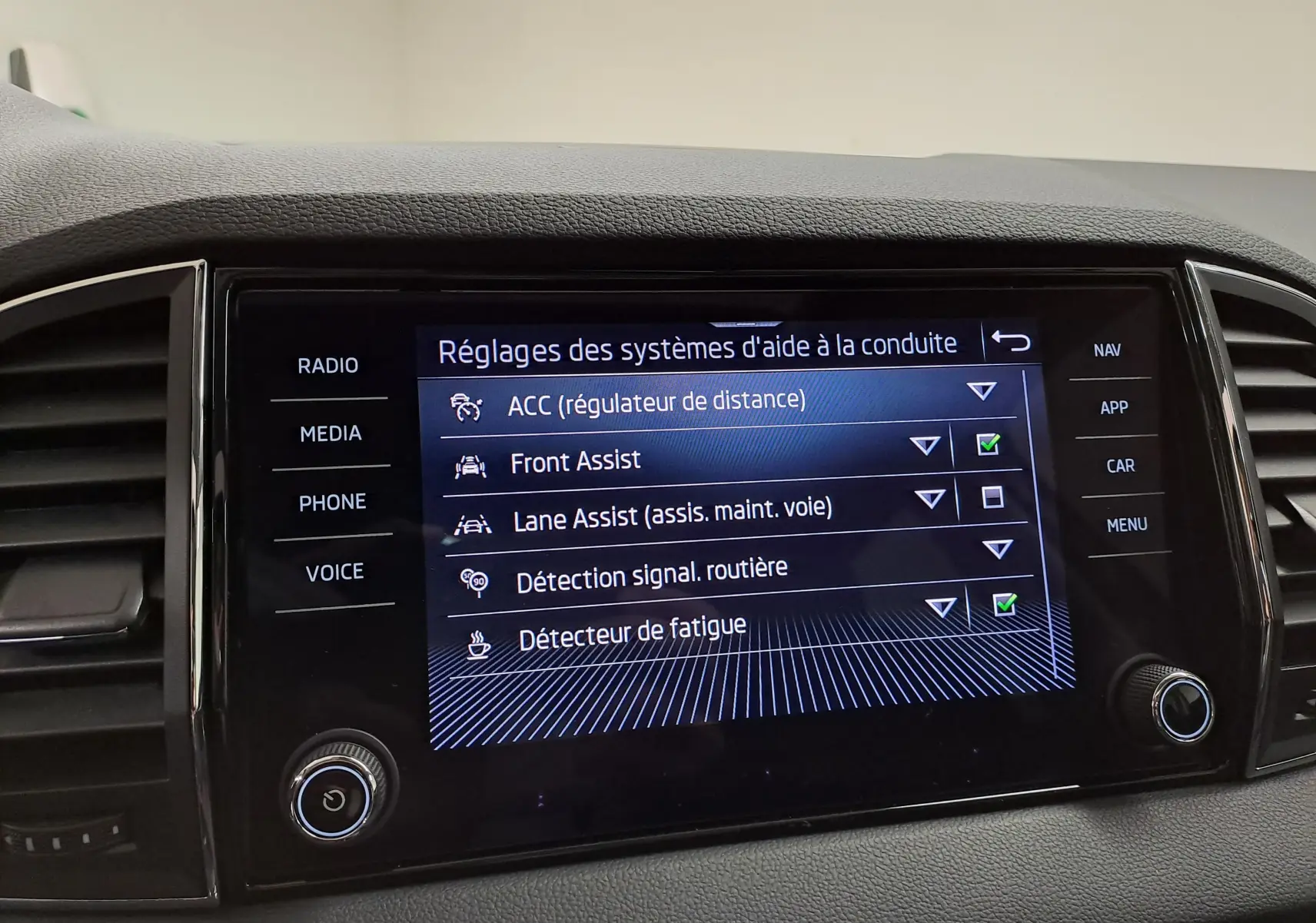 Écran central tactile du Skoda Karoq 2023 affichant les réglages des aides à la conduite.