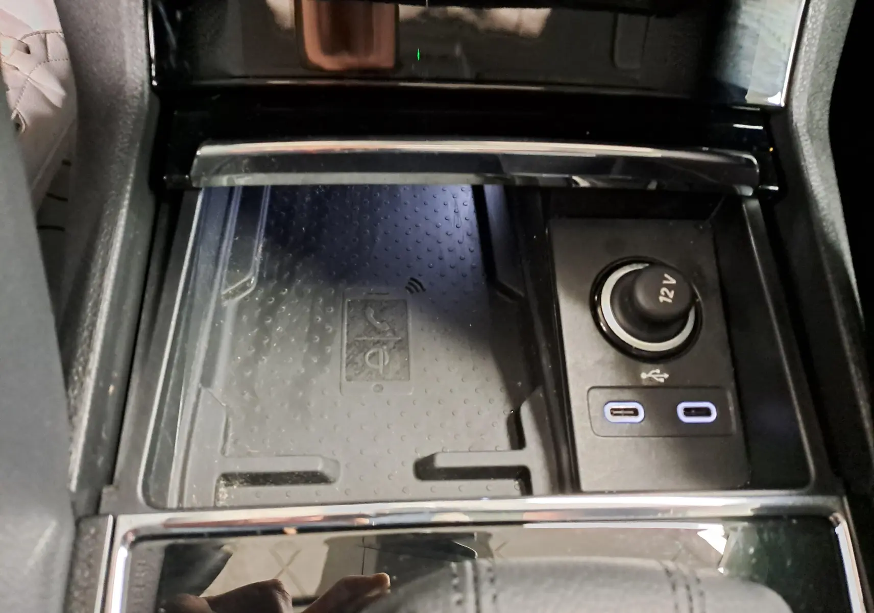 Gros plan sur la console centrale du Skoda Karoq 2023, montrant la phonebox à recharge par induction et prises USB-C.