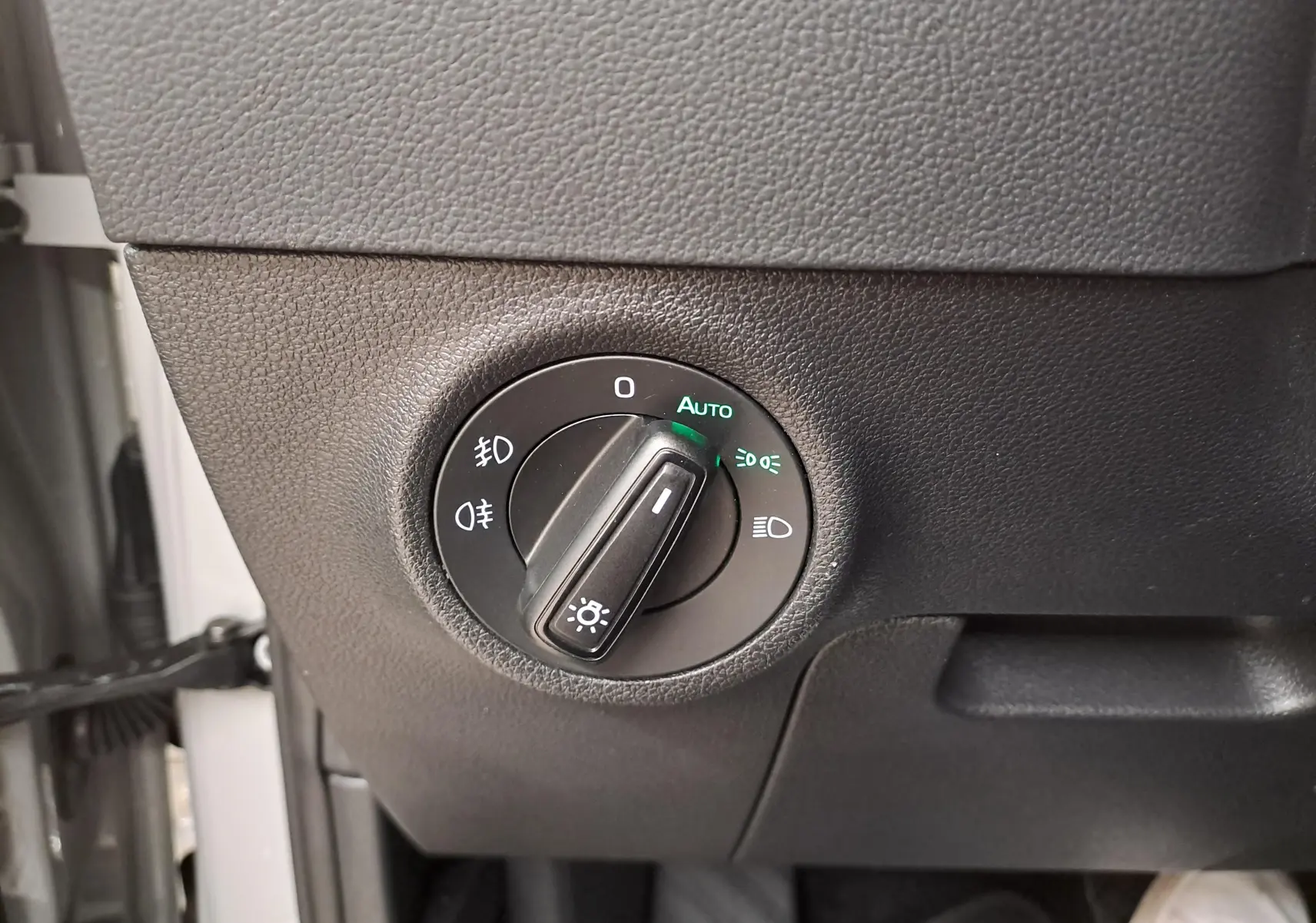 Gros plan sur le bouton de commande des phares du Skoda Karoq 2023 gris perle, avec réglage automatique activé.