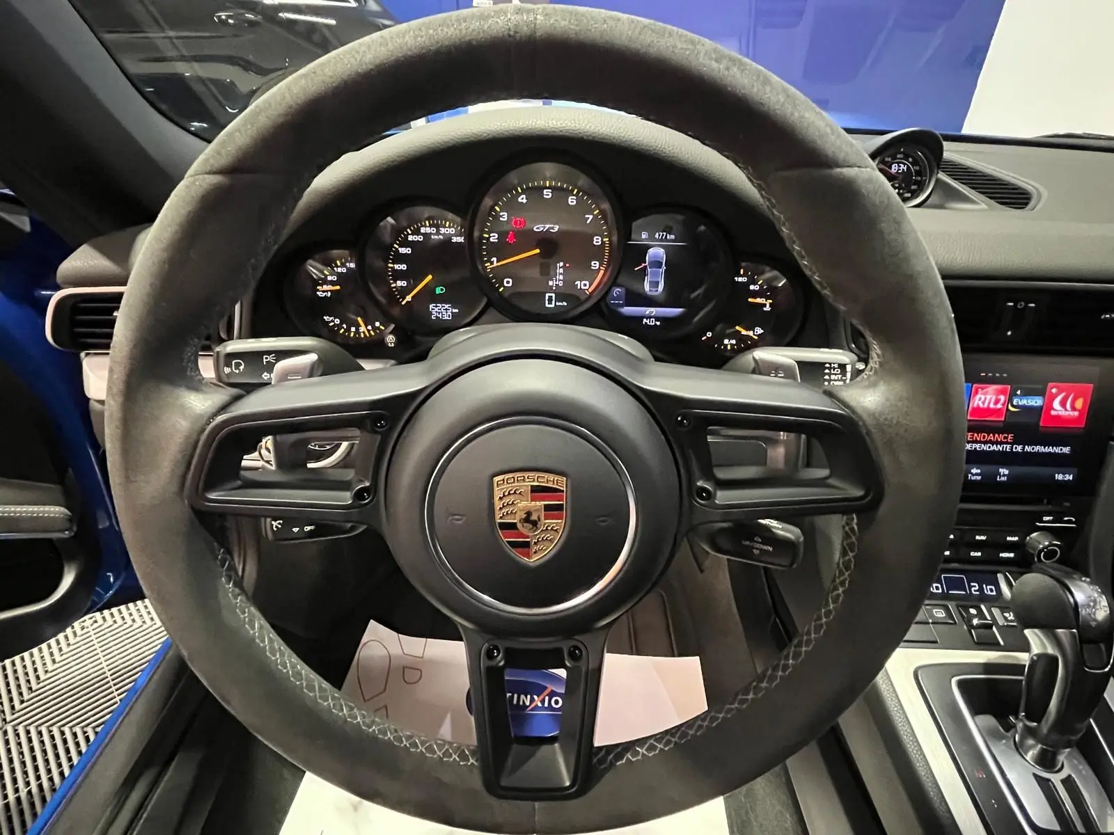 Vue intérieure centrée sur le volant sport alcantara et le tableau de bord de la Porsche 911 GT3 bleu saphir.