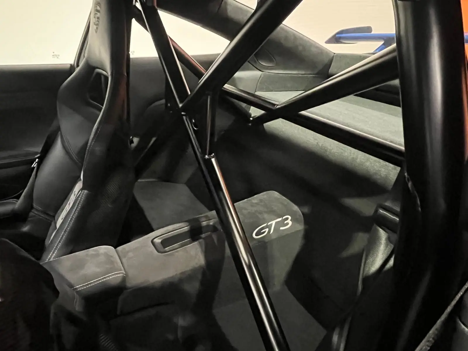 Vue intérieure arrière droite de la Porsche 911 GT3 2018, montrant l'arceau de sécurité et les sièges baquets noirs avec logo GT3.