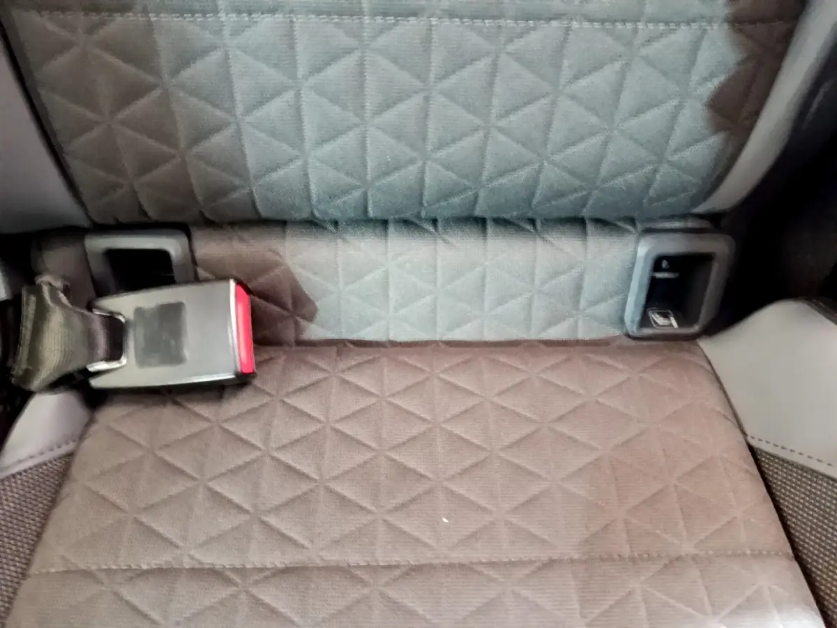 Gros plan sur la banquette arrière grise à motif losange du Volkswagen T-Cross noir, avec ceinture de sécurité visible.