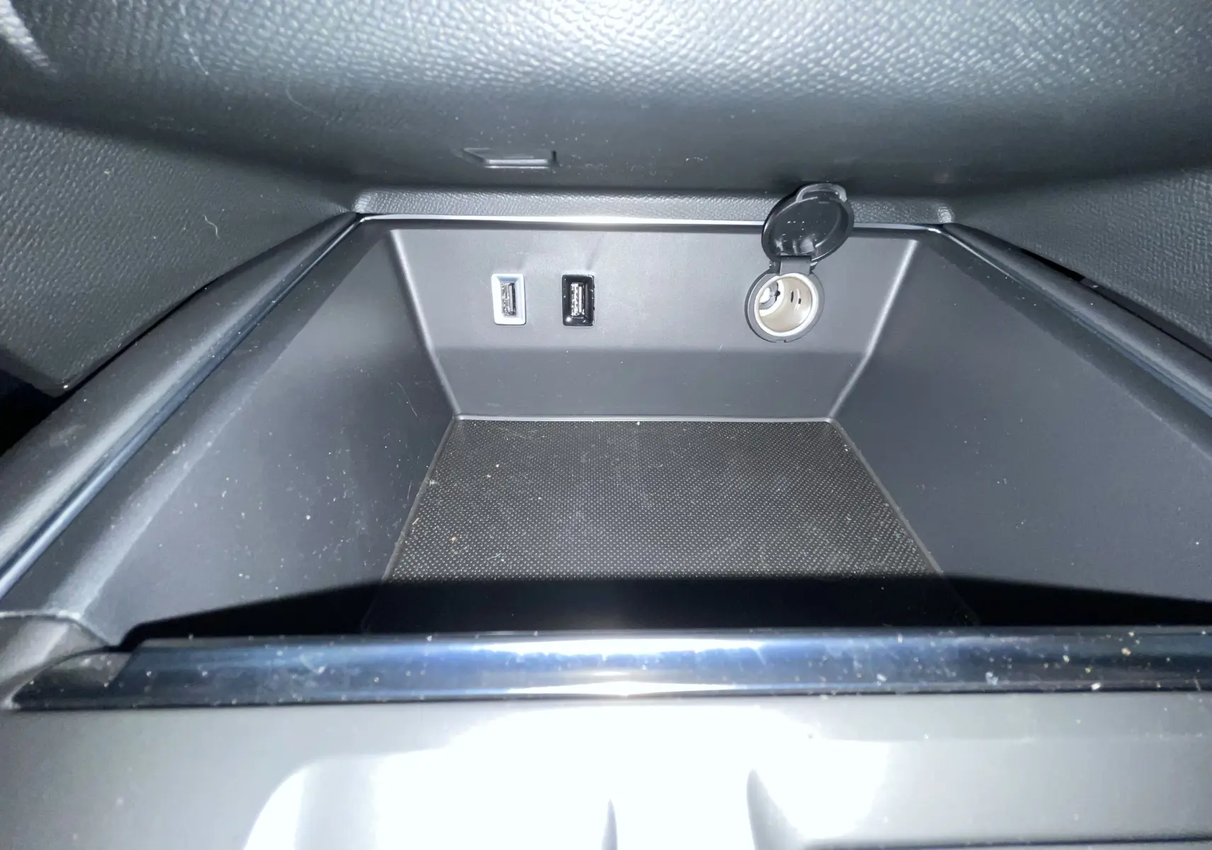 Gros plan sur la prise 12V et ports USB dans le rangement intérieur du Citroën C5 Aircross hybride gris platinium.