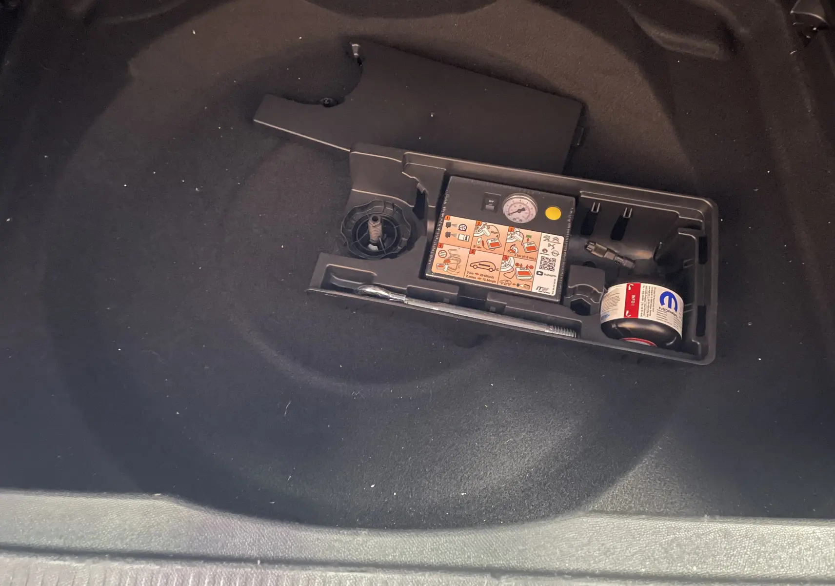 Gros plan sur le compartiment de rangement sous le coffre du Citroën C5 Aircross gris platinium, montrant le kit de réparation pneus.