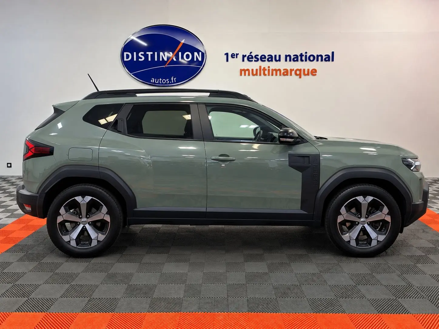 Profil côté droit du Dacia Duster 2026 vert cèdre, version hybride, avec jantes alliage et détails noirs contrastants.