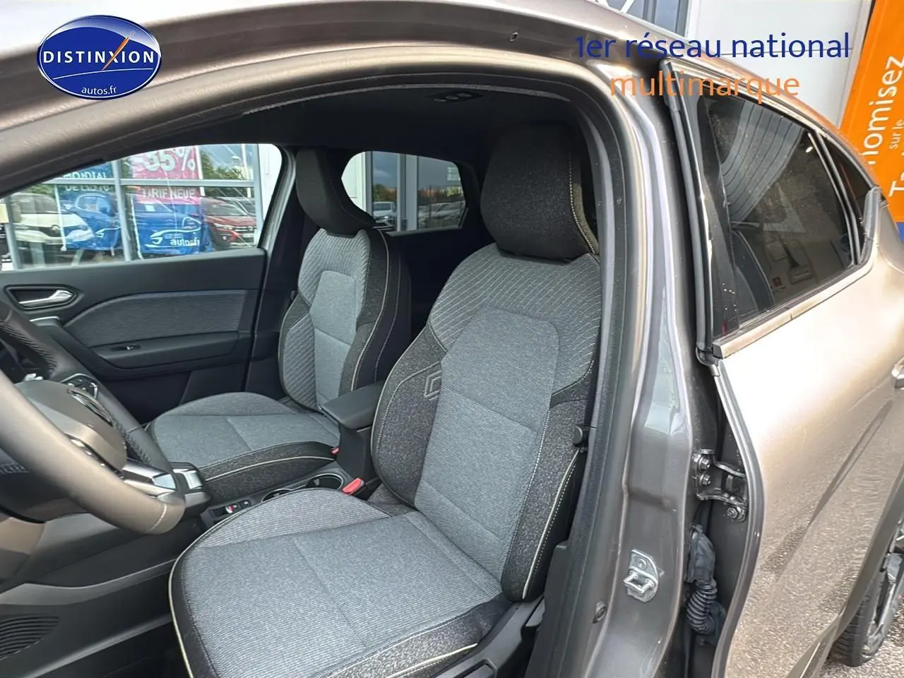 Intérieur avant du Renault Captur gris cassiopée 2025, sièges tissu gris et accoudoir central visible côté droit.