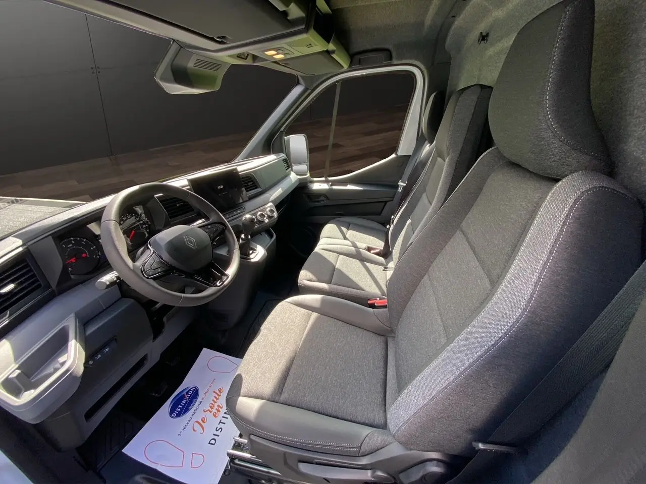 Vue intérieure côté conducteur du Renault Master 2025, montrant la sellerie tissu gris foncé et le tableau de bord moderne.