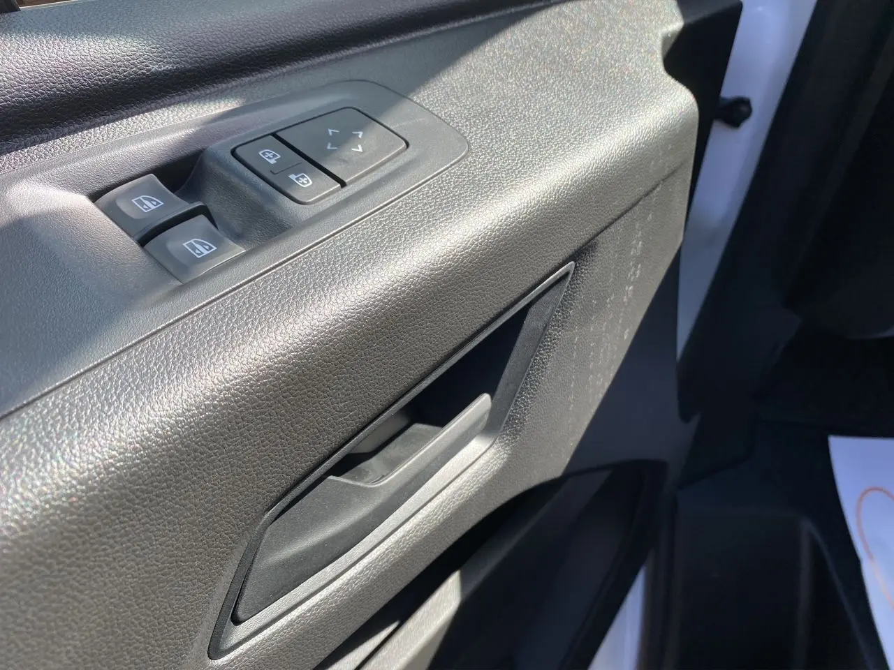 Poignée et commandes des vitres côté conducteur du Renault Master blanc 2025, intérieur en plastique noir texturé.