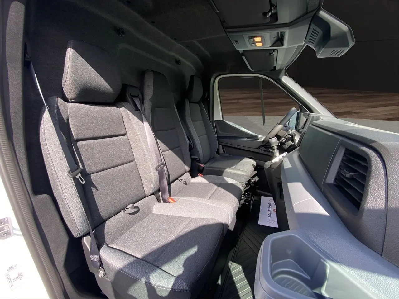 Intérieur du Renault Master 2025 vu côté passager, banquette tissu gris foncé avec rangements et tableau de bord gris.