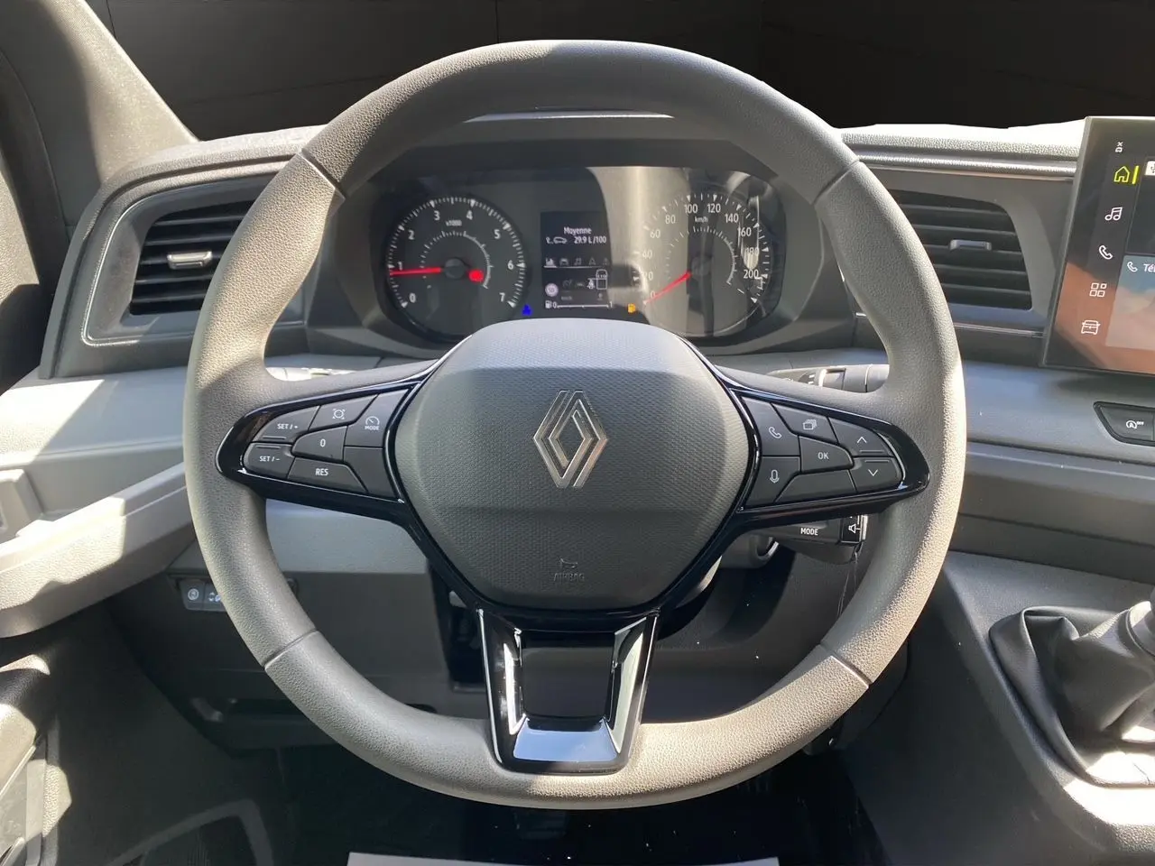 Vue rapprochée du volant gris et noir avec logo Renault, tableau de bord et levier de vitesse manuel du Master 2025.