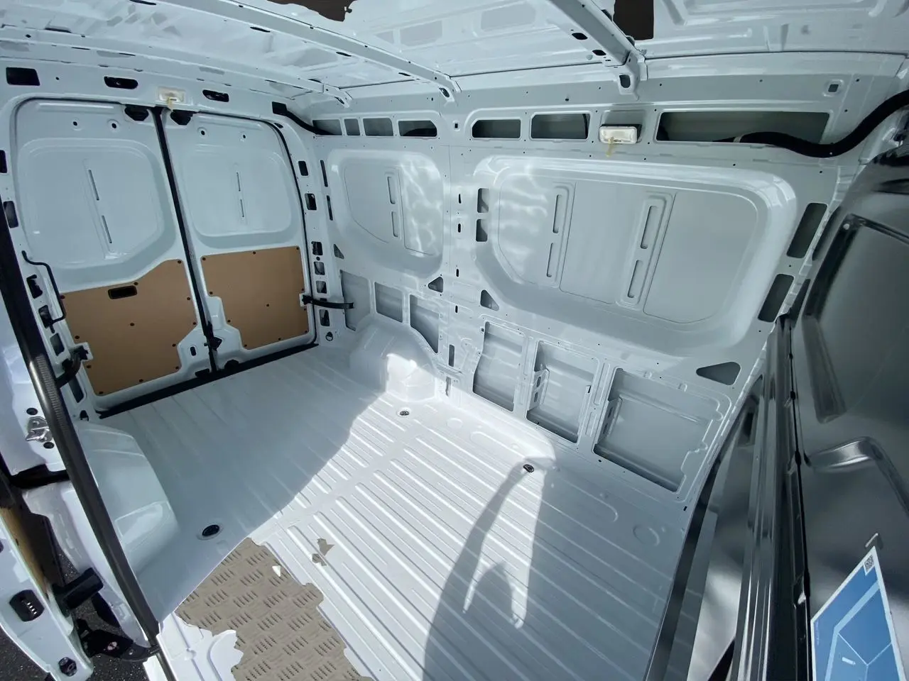 Intérieur du coffre blanc du Renault Master 2025, vue arrière avec portes tôlées ouvertes et plancher métallique.