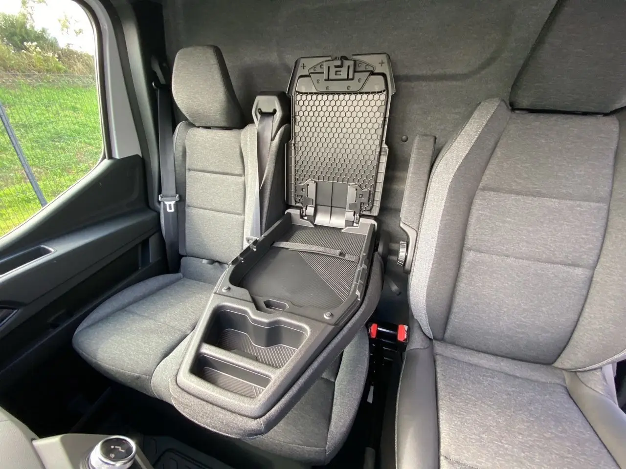 Intérieur du Renault Master 2025 montrant la banquette passager grise avec bureau mobile déplié entre les sièges avant.