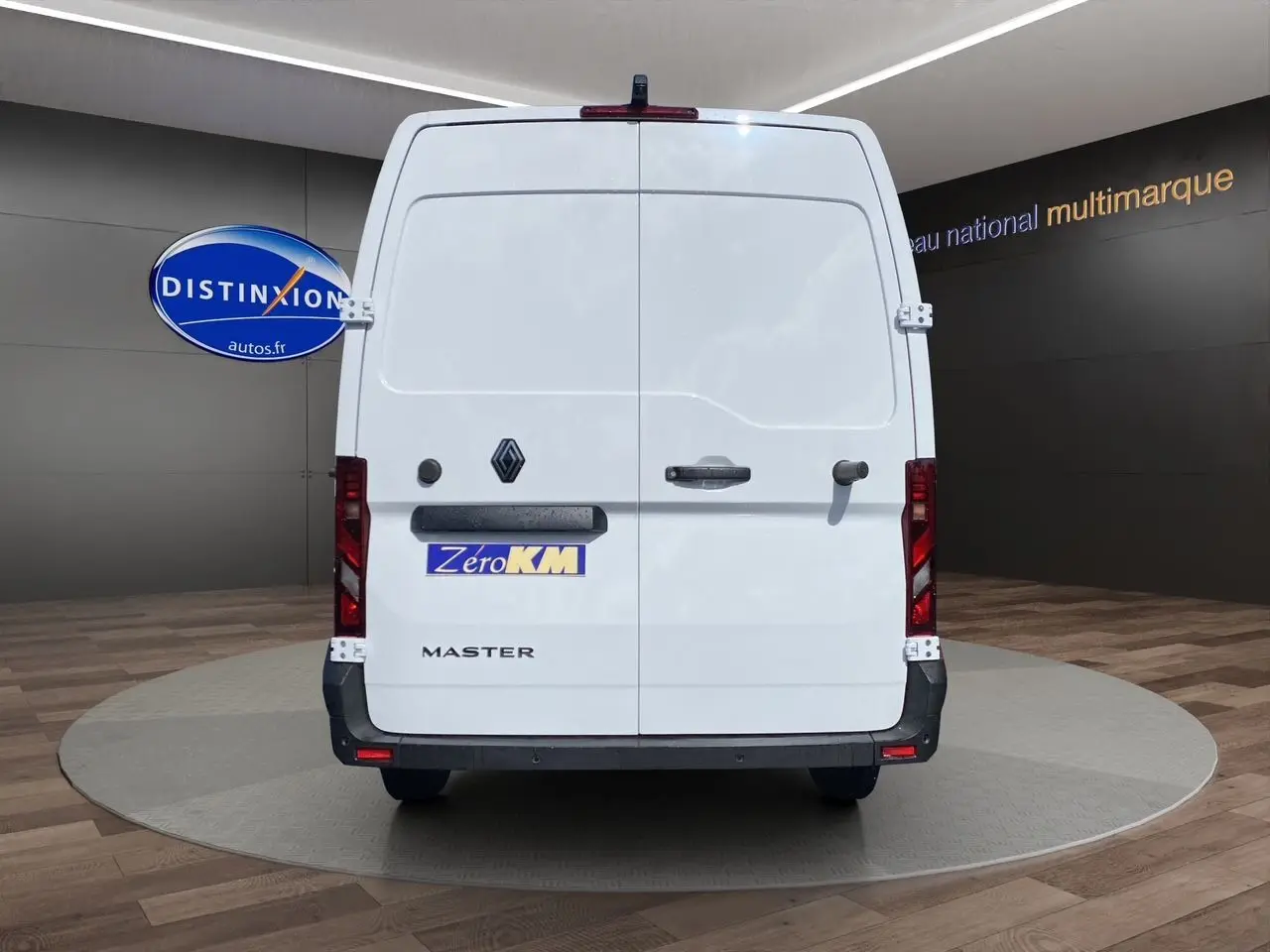 Vue arrière d’un utilitaire Renault Master blanc avec portes arrière tôlées et logo distinctif sur fond de showroom.