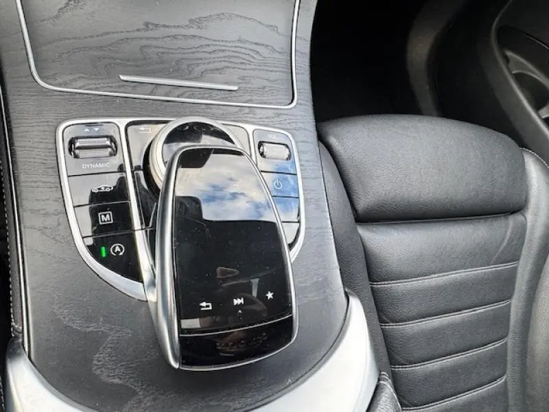 Gros plan sur la console centrale en bois noir et cuir noir du Mercedes GLC Coupé 350 d avec commandes tactiles et siège avant.