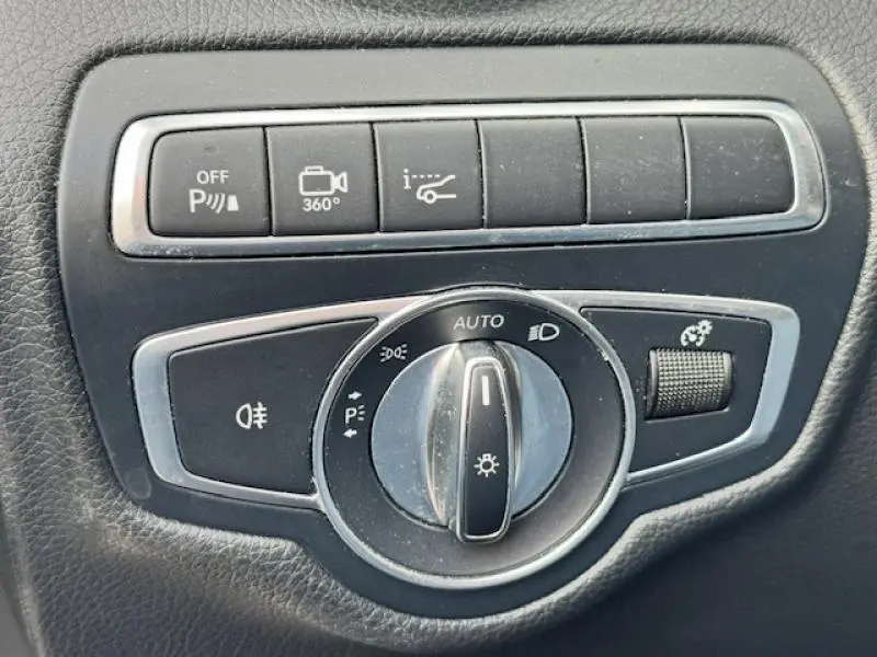 Gros plan sur les commandes d’éclairage et d’aide au stationnement du Mercedes GLC Coupé blanc polaire, intérieur cuir noir.