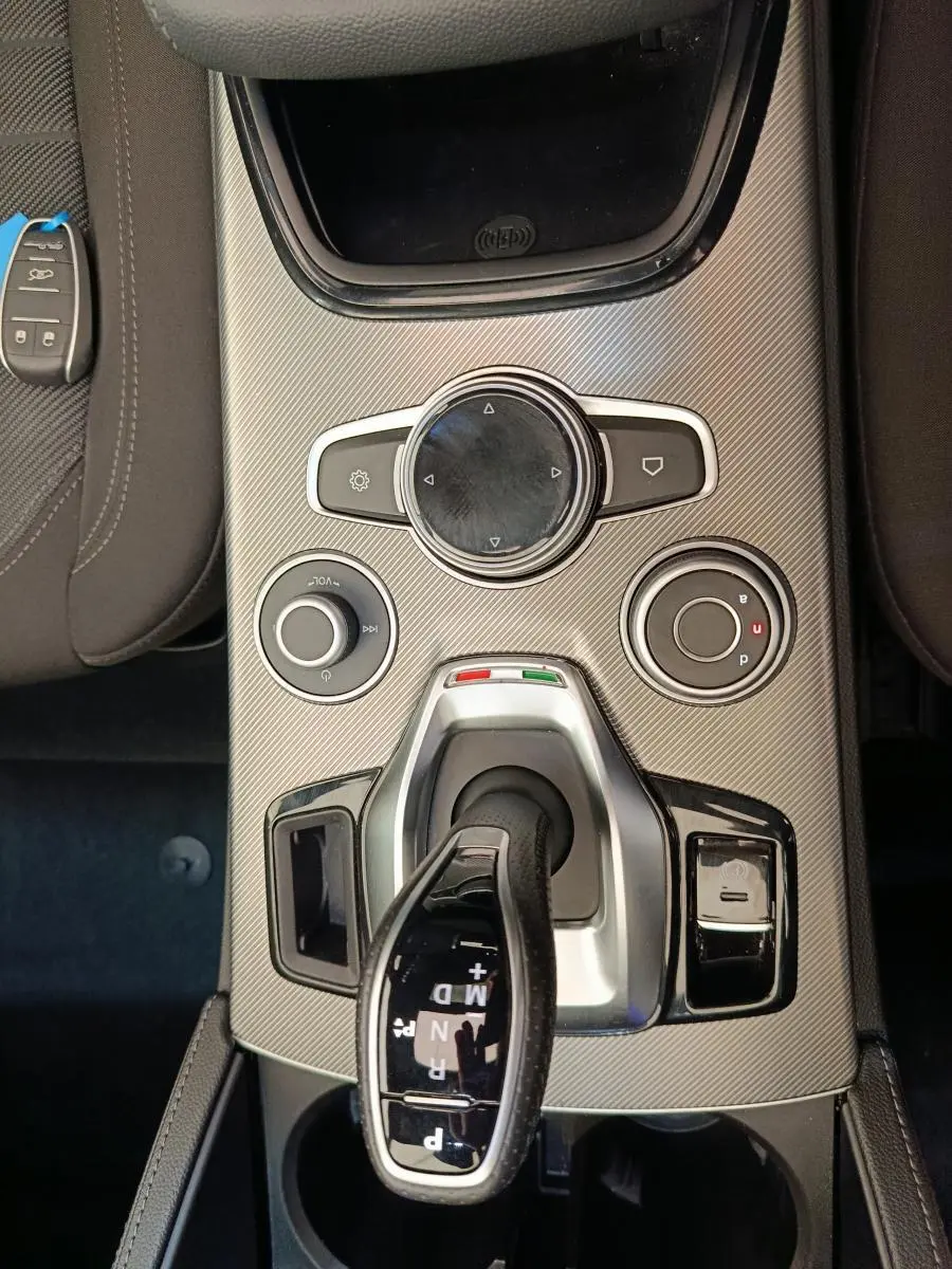 Vue plongeante sur la console centrale gris foncé de l'Alfa Romeo Stelvio 2024 avec levier de vitesses automatique et molette de contrôle.