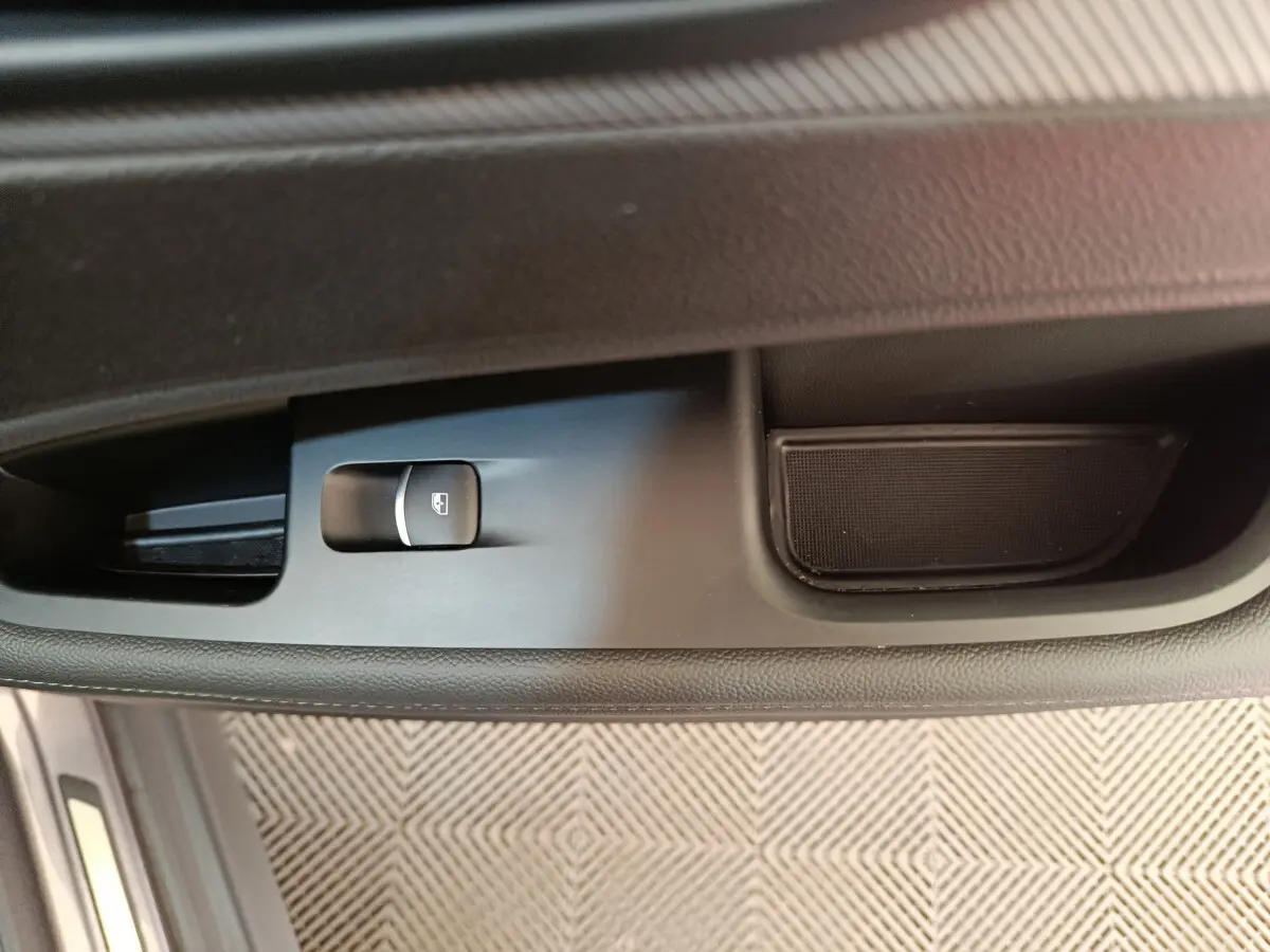 Gros plan sur le bouton de commande de la vitre côté gauche de l'Alfa Romeo Stelvio gris foncé, intérieur noir.