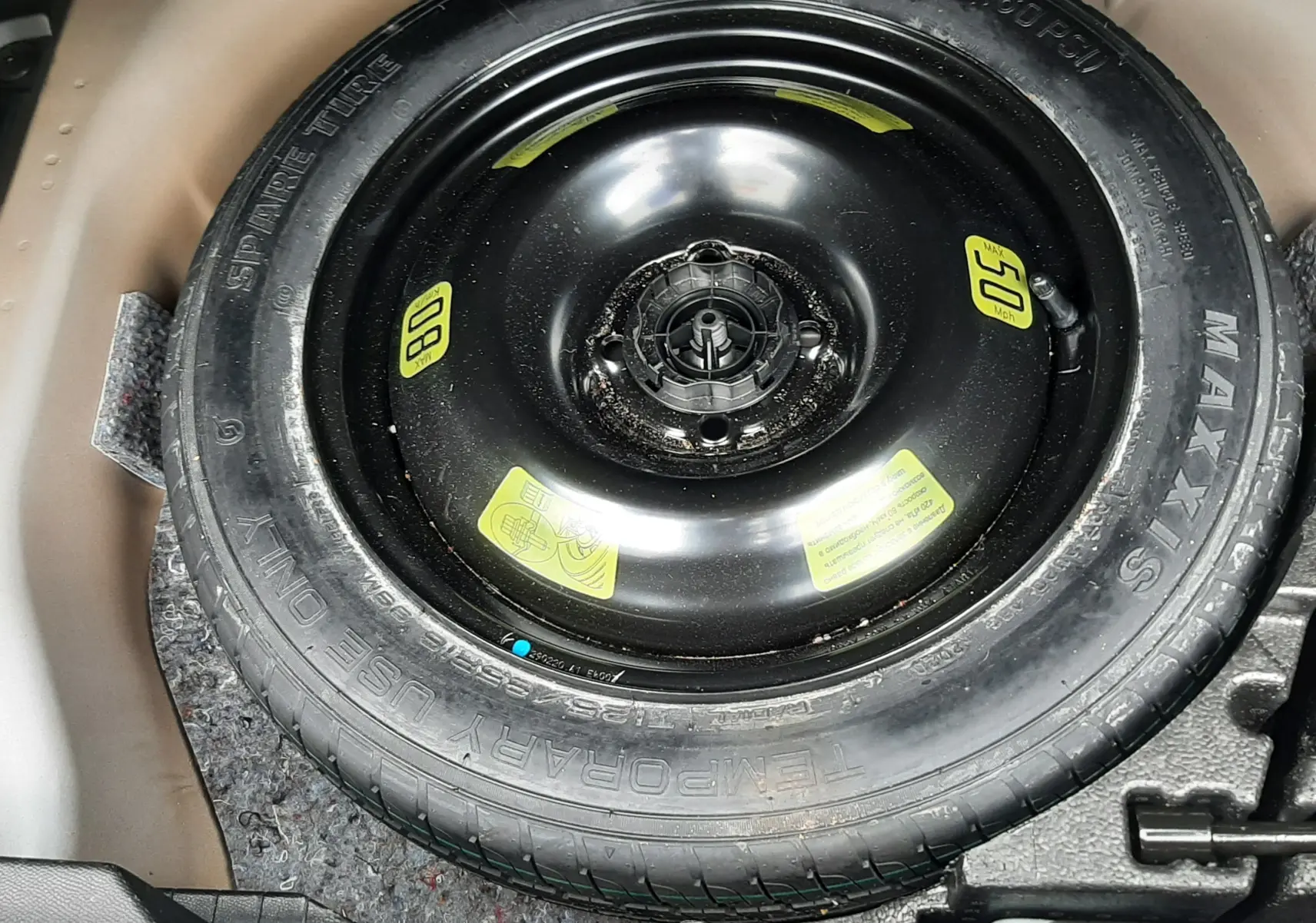 Gros plan sur la roue de secours noire dans le coffre d’un Peugeot 2008 gris Artense de 2020.