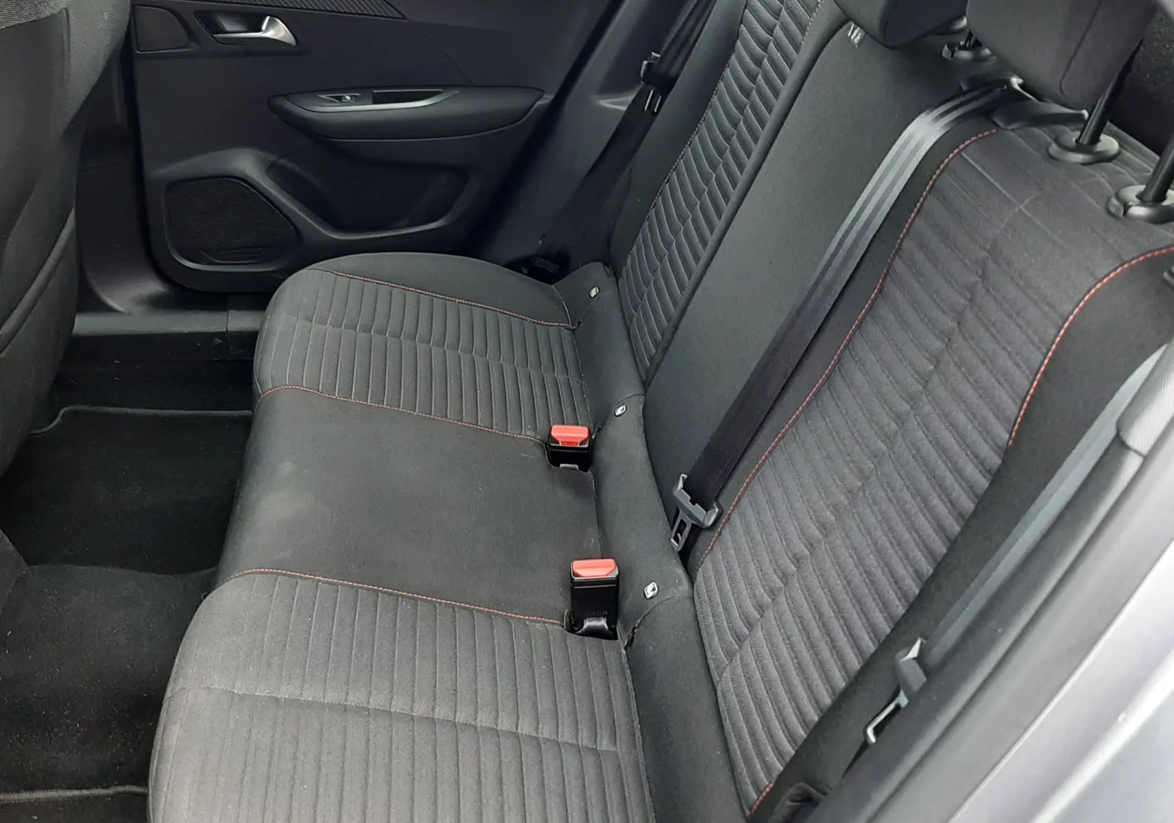 Vue intérieure côté droit des sièges arrière en tissu gris foncé avec surpiqûres rouges du Peugeot 2008 gris 2020.