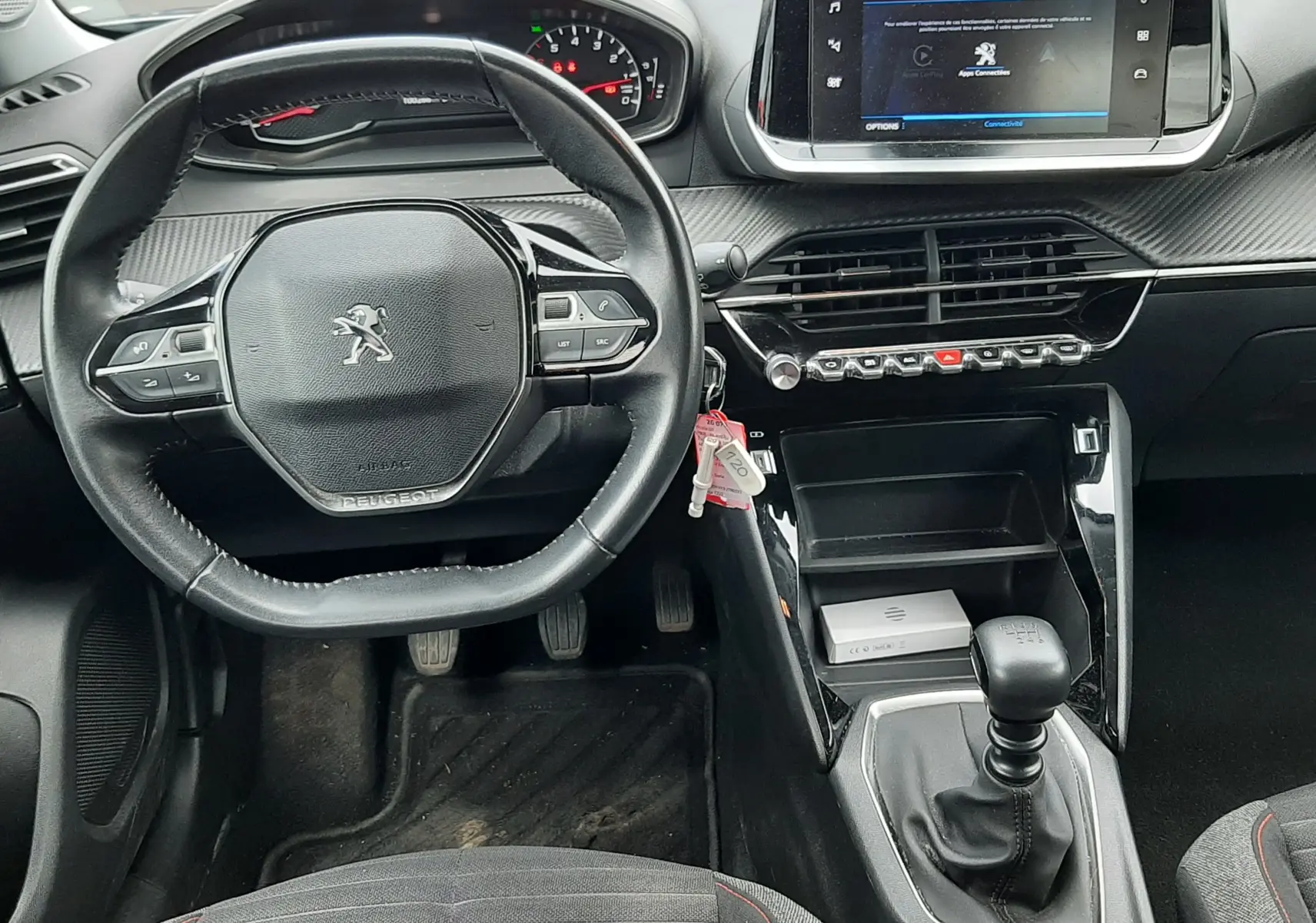 Vue intérieure avant du Peugeot 2008 2020, tableau de bord gris avec volant compact, écran tactile et levier de vitesse manuel.