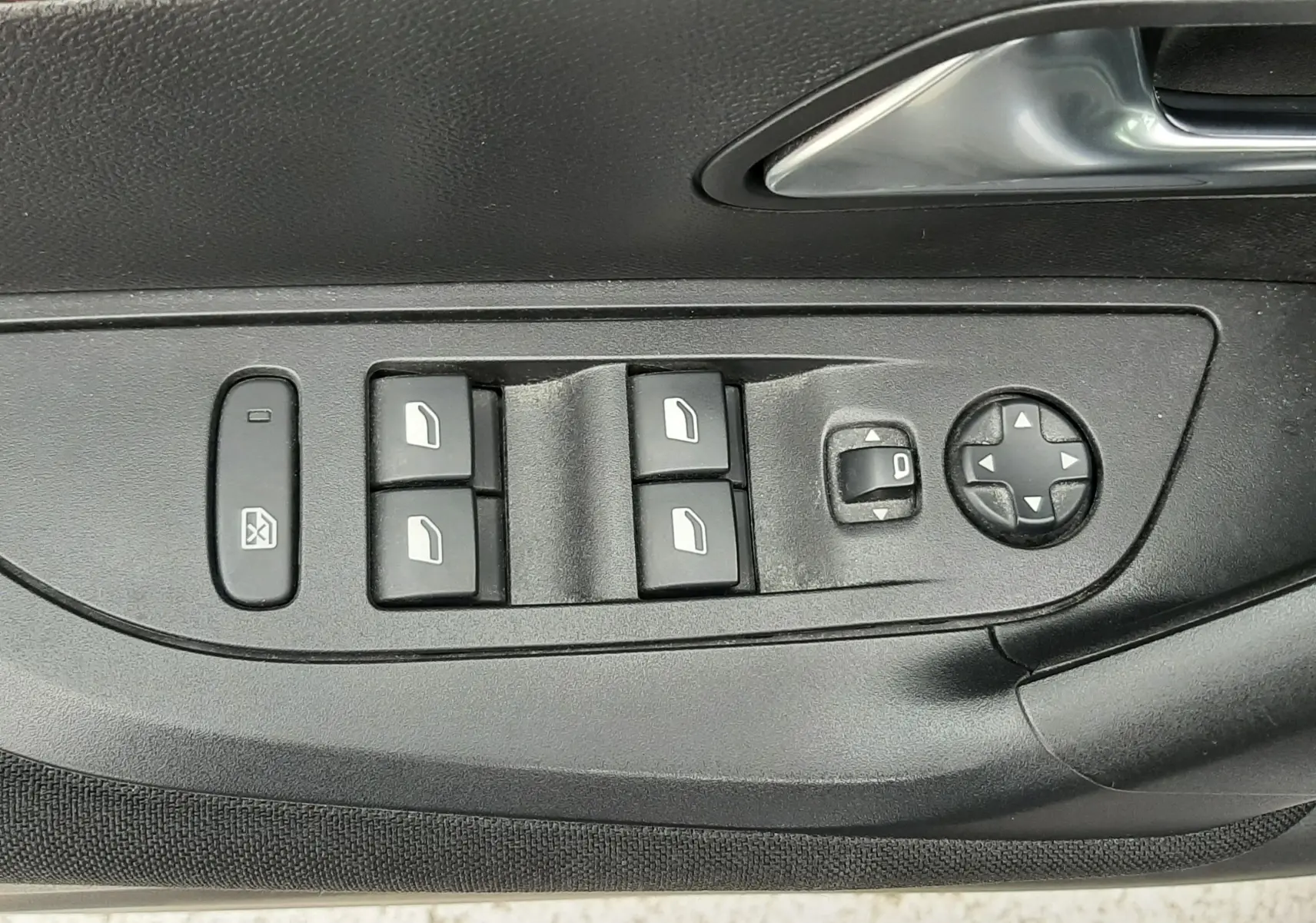 Gros plan sur les commandes de lève-vitres et réglage des rétroviseurs côté conducteur d’un Peugeot 2008 gris Artense.