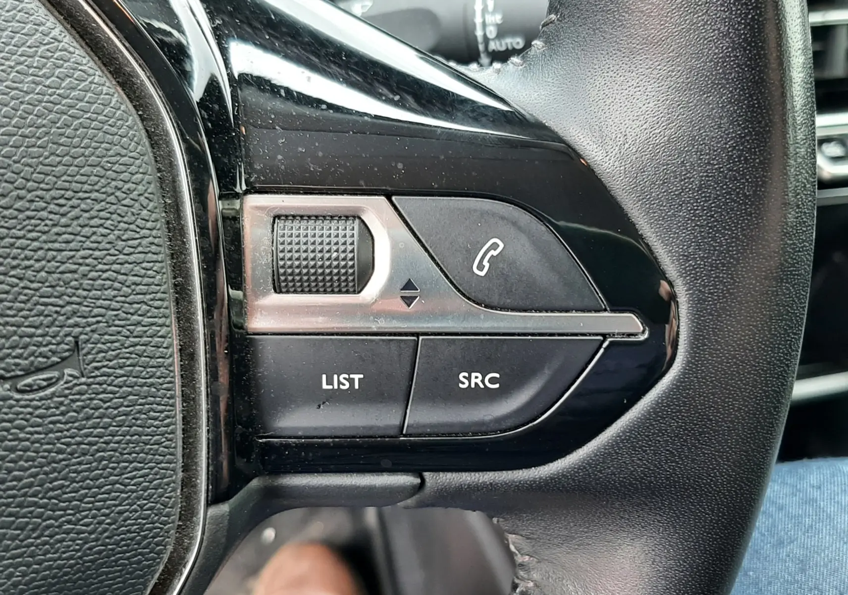 Gros plan sur les commandes gauche du volant noir du Peugeot 2008 2020, avec boutons LIST, SRC et symbole téléphone.