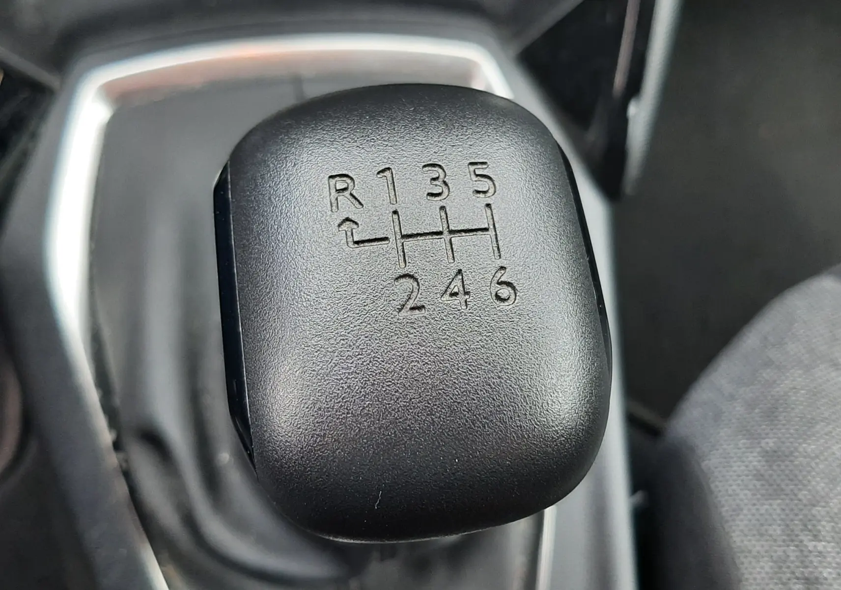 Gros plan sur le levier de vitesses manuel noir du Peugeot 2008 gris Artense, montrant la grille à 6 rapports et la marche arrière.