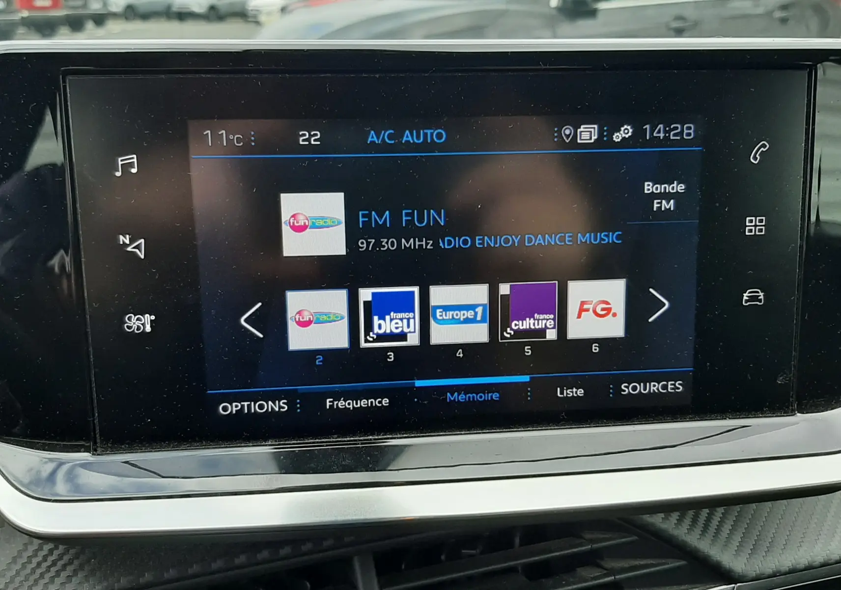 Vue intérieure sur l'écran tactile multimédia du Peugeot 2008 gris Artense, affichant les stations radio FM avec commandes tactiles.